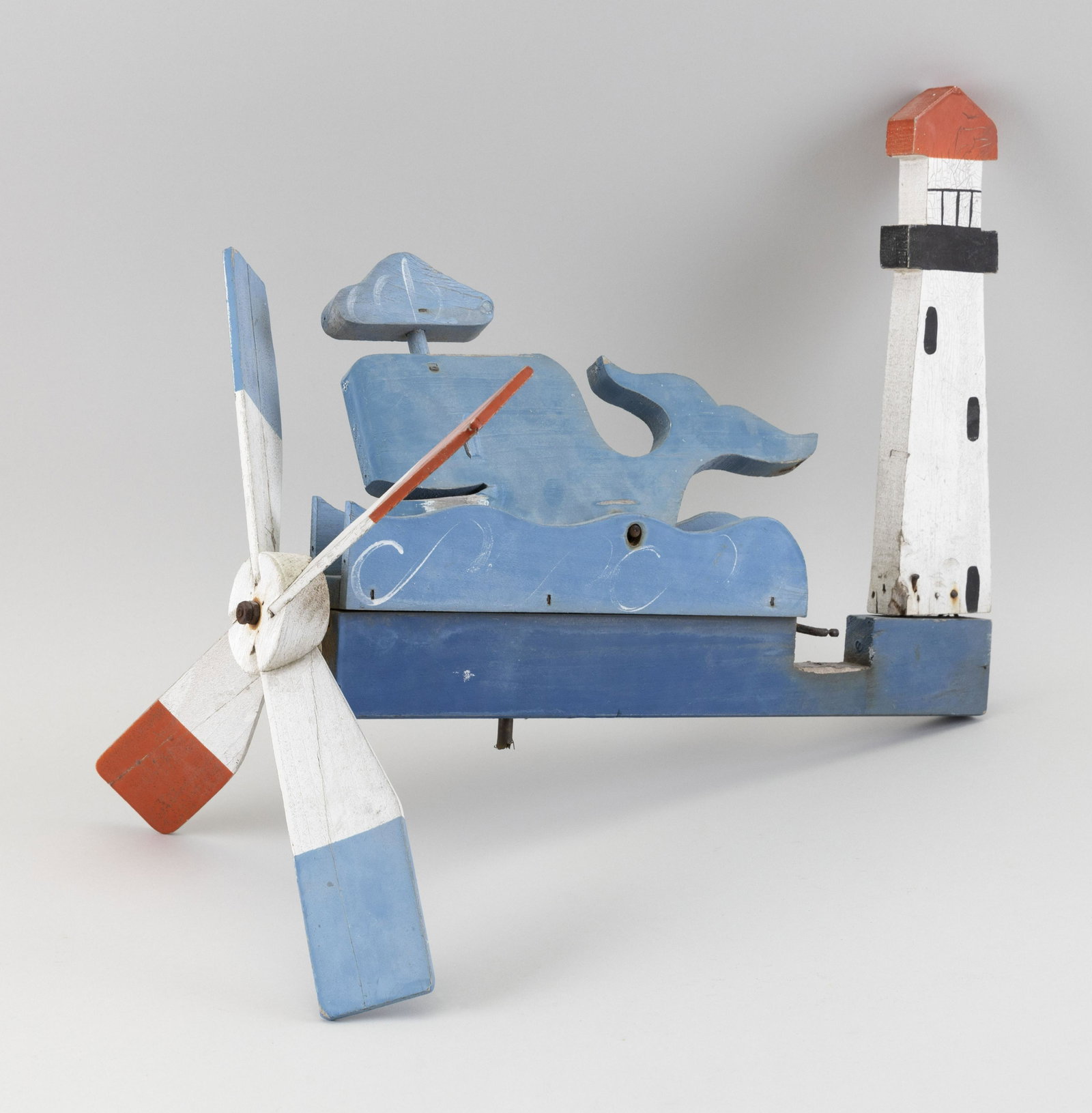 CARVED AND PAINTED NAUTICAL WHIRLIGIG Circa 1987 Height: CARVED AND PAINTED NAUTICAL WHIRLIGIG Circa 1987 In the form of a whale off a lighthouse. Labeled “Walton’s Woodcraft”. Height 11.5". Length 15.25".