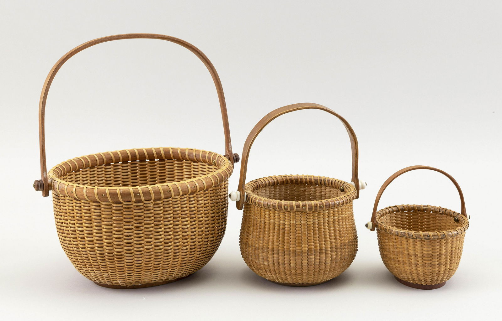 THREE SMALL NANTUCKET BASKETS Contemporary Heights to: THREE SMALL NANTUCKET BASKETSContemporaryAll with swing handles. Oval basket and bulbous round basket by Henry Haug, both signed on undersides, and an oval basket inscribed on underside "Made for