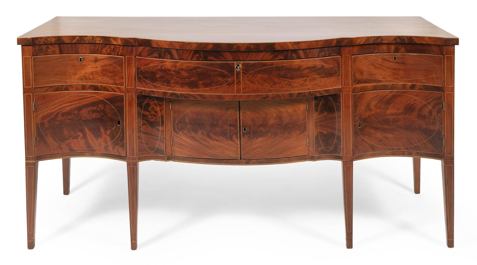 HEPPLEWHITE SERPENTINE SIDEBOARD America, Circa 1790: HEPPLEWHITE SERPENTINE SIDEBOARD America, Circa 1790 In mahogany and mahogany veneer, with select flame mahogany veneer to front surfaces. Three drawers over four cupboard doors and tapered legs, all 