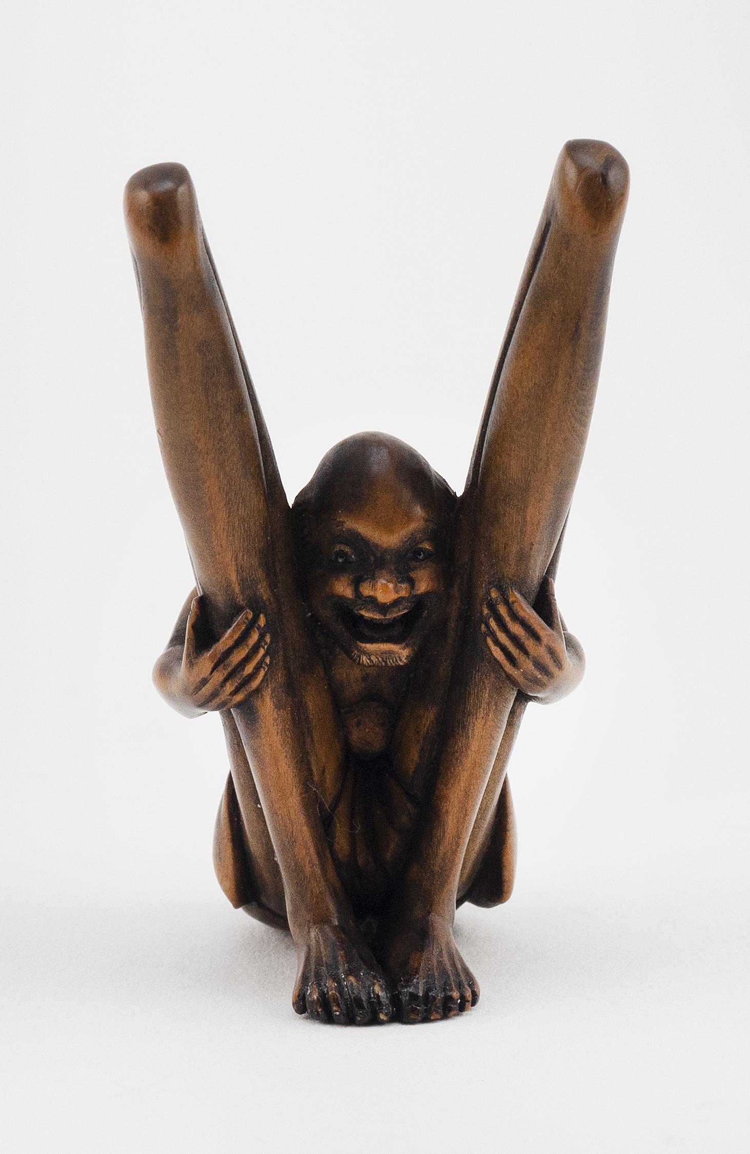 JAPANESE WOOD NETSUKE BY SHOKO 19th Century Height 2".: JAPANESE WOOD NETSUKE BY SHOKO19th CenturyAn Ashinaga peering through his bent legs. Signed.Height 2". Provenance:Private Western Massachusetts Collection.