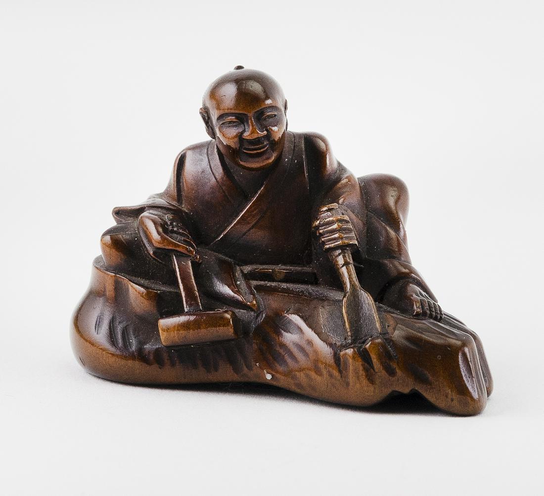 JAPANESE WOOD NETSUKE Meiji Period Height 1.5".: JAPANESE WOOD NETSUKEMeiji PeriodA seated man carving the base upon which he sits into the shape of a foot. Signed.Height 1.5". Provenance:Private Wisconsin Collection.