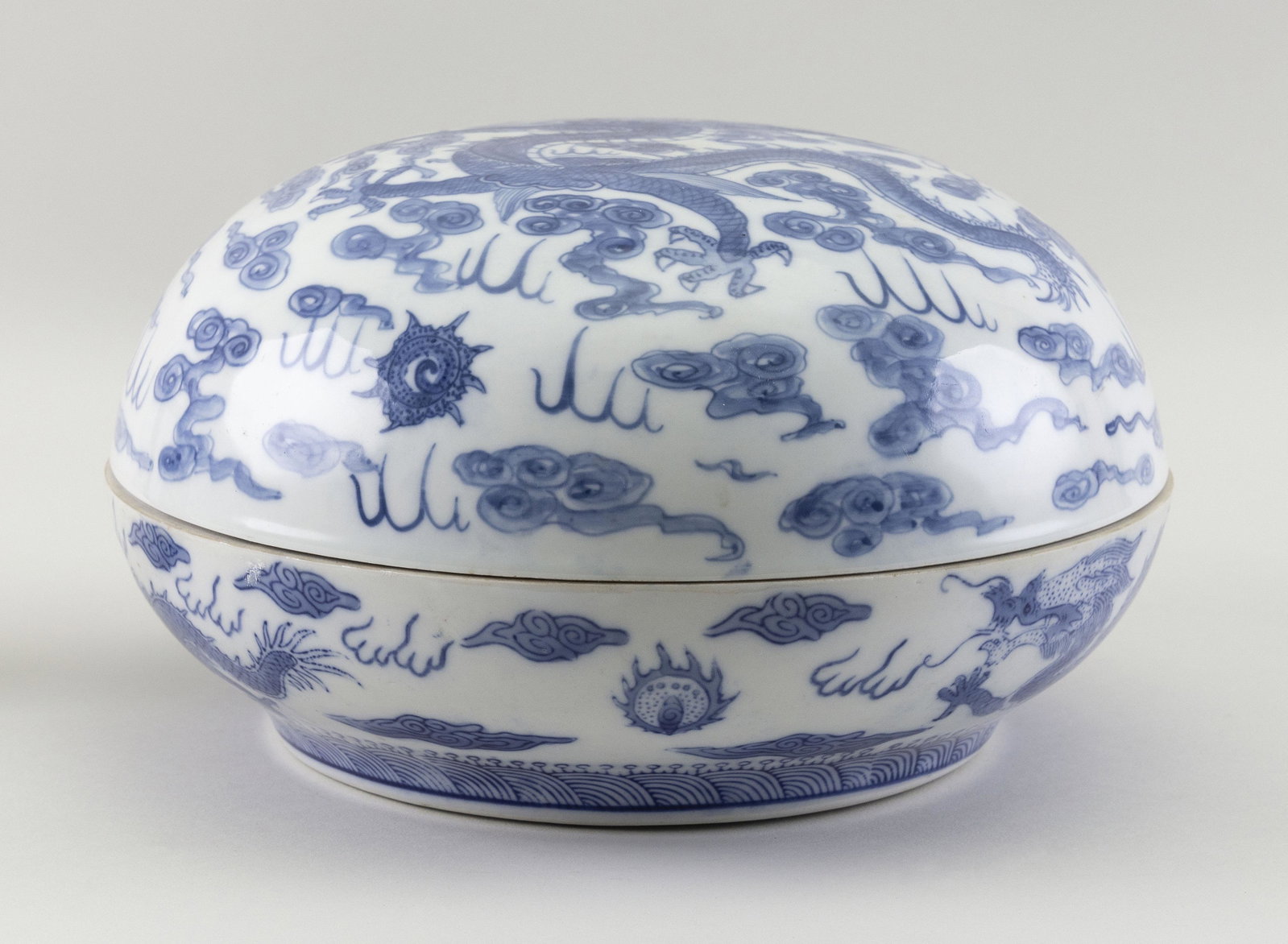 CHINESE BLUE AND WHITE PORCELAIN COVERED BOX 20th: CHINESE BLUE AND WHITE PORCELAIN COVERED BOX 20th Century Exterior with five-clawed dragon and fiery pearl decoration. Interior with bat and shou rondel. Height 6”. Diameter 11”.