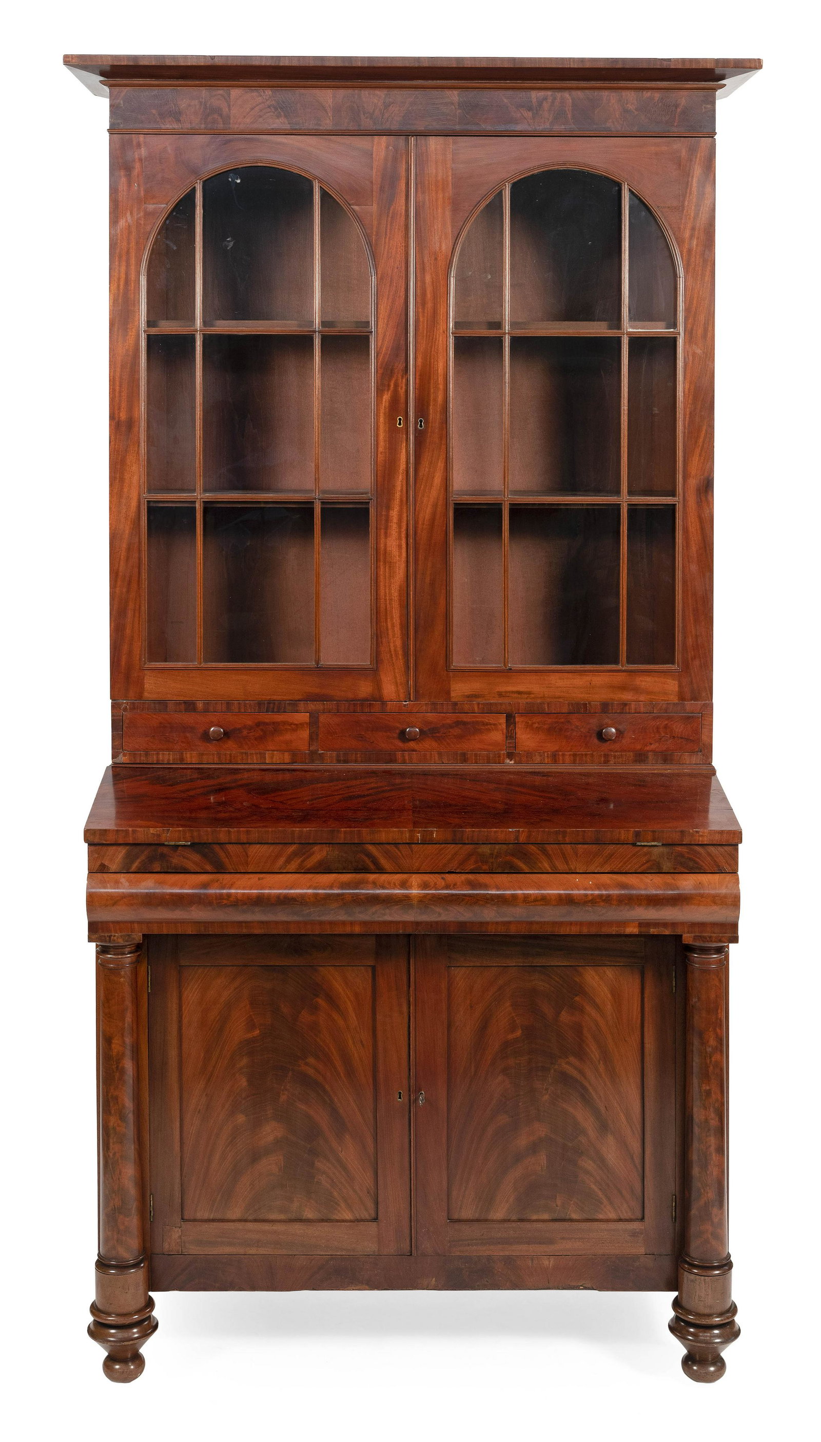 EMPIRE TWO-PART SECRETARY Circa 1830 Height 90”.: EMPIRE TWO-PART SECRETARY Circa 1830 In mahogany and mahogany veneer, with select mahogany veneer used throughout. Upper case with flared cornice, two arched glazed paneled doors and three side-by-sid