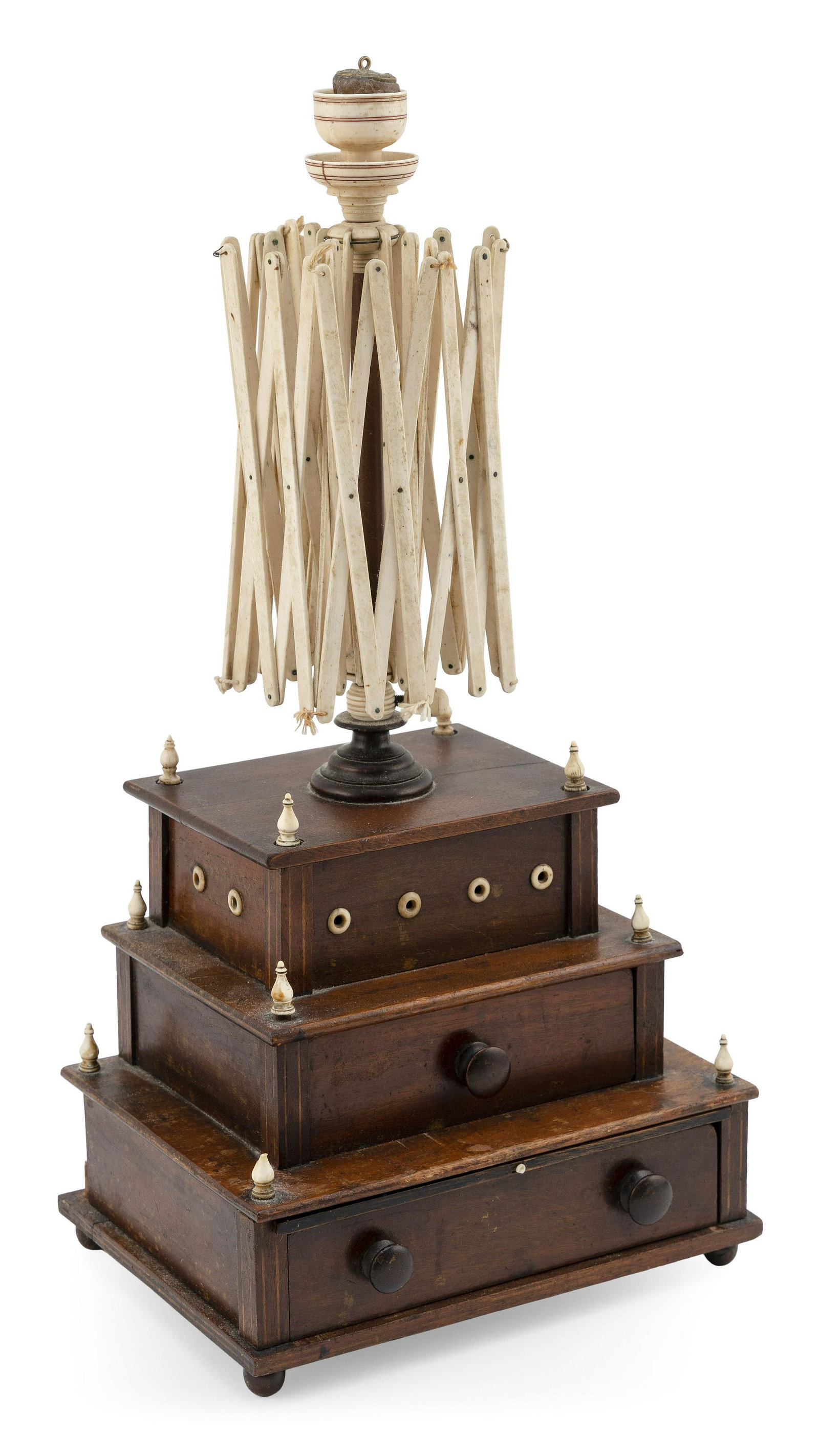 SEWING BOX SURMOUNTED BY A SWIFT Mid-19th Century: SEWING BOX SURMOUNTED BY A SWIFT Mid-19th Century Three-tier walnut box with turned bone finials at corners, line inlay along perimeters, a pull-out mirror, and ball feet. Lift-off top surmounted by a