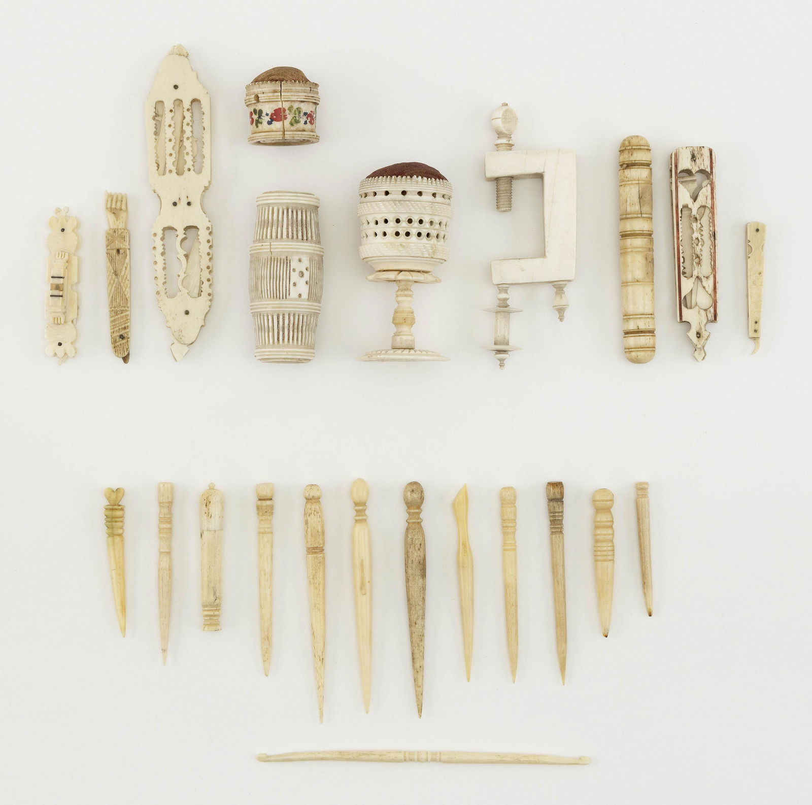 APPROX. TWENTY-THREE BONE SEWING ITEMS 19th Century: APPROX. TWENTY-THREE BONE SEWING ITEMS 19th Century Eleven bodkins, a hook, five utility knives, three needle cases, two pincushions and a clamp. Most with decorative turnings or carvings, including a