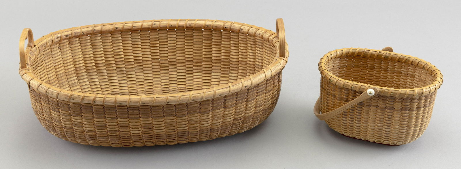 TWO OVAL NANTUCKET BASKETS Contemporary 5.25” x 4” and 12” x 7.75”. (1 of 3)