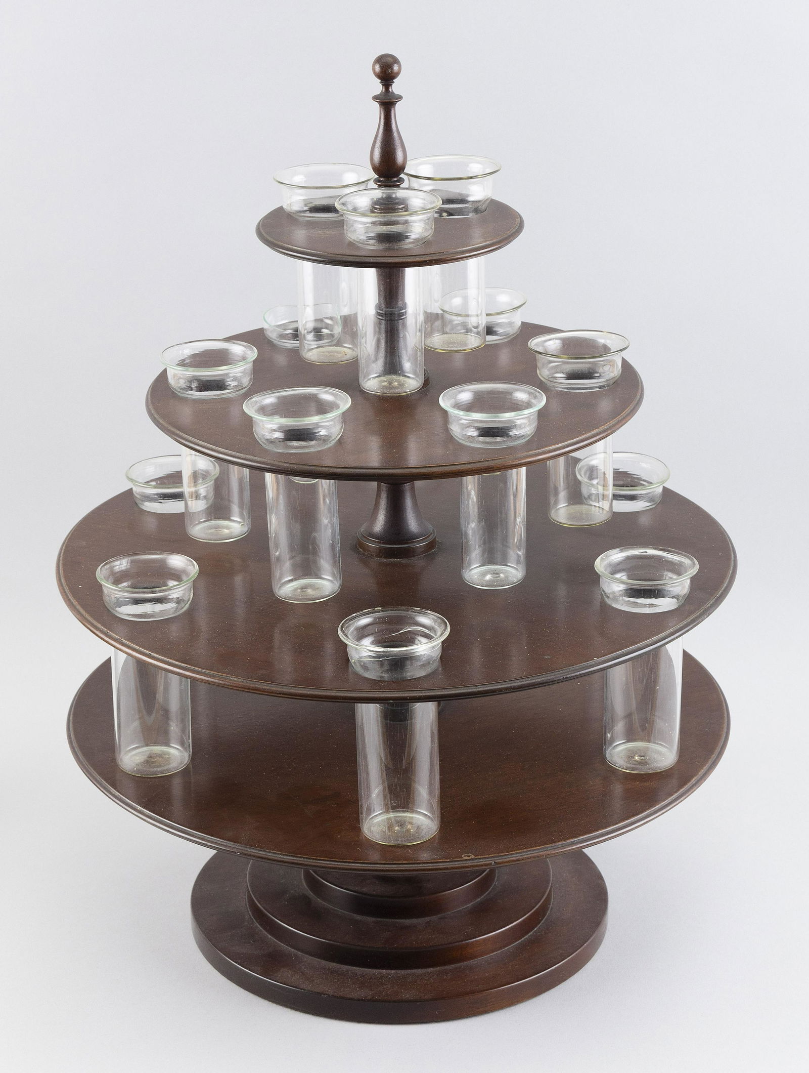 FOUR-TIER MAHOGANY CENTERPIECE Early 20th Century Total height 18.5”. Diameter 14”.: FOUR-TIER MAHOGANY CENTERPIECEEarly 20th CenturyFitted with fifteen glass containers, possibly used as bud vases.Total height 18.5”. Diameter 14”.