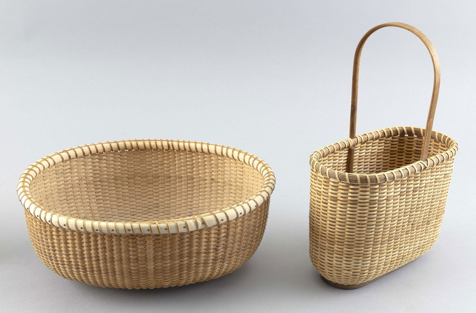 TWO OVAL NANTUCKET-STYLE BASKETS Contemporary 7” x 4” and 10.25” x 8.25”. (1 of 3)