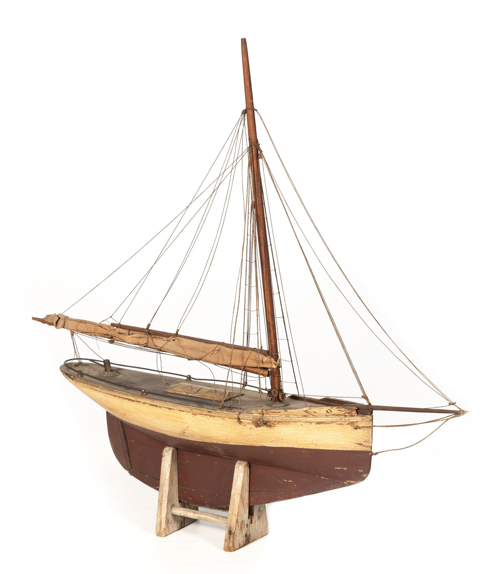 EARLY POND MODEL OF A GAFF-RIGGED SLOOP Late 19th/Early 20th Century Height on cradle 29.5”.: EARLY POND MODEL OF A GAFF-RIGGED SLOOP Late 19th/Early 20th Century Off-white hull with red bottom. Displayed on a wooden cradle. Height on cradle 29.5”. Length 28.5”.