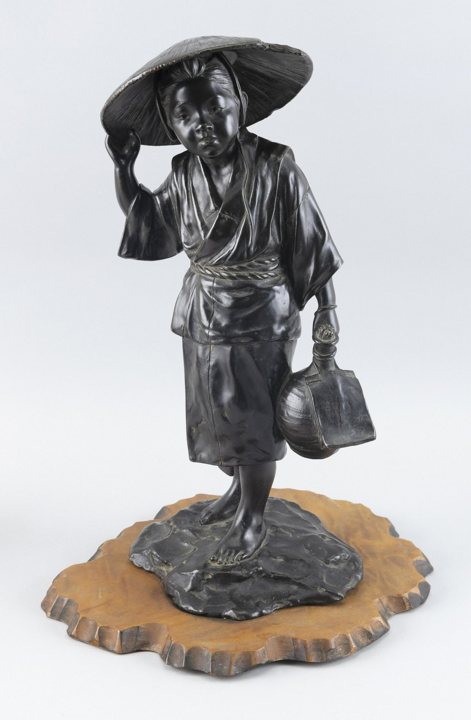 JAPANESE BRONZE FIGURE OF A FARMER Late Meiji Period Height 16". Base length 11".: JAPANESE BRONZE FIGURE OF A FARMER Late Meiji Period Holding a sake bottle in one hand and his hat in the other. Signed at base. Standing on an attached wood base. Height 16". Base length 11"