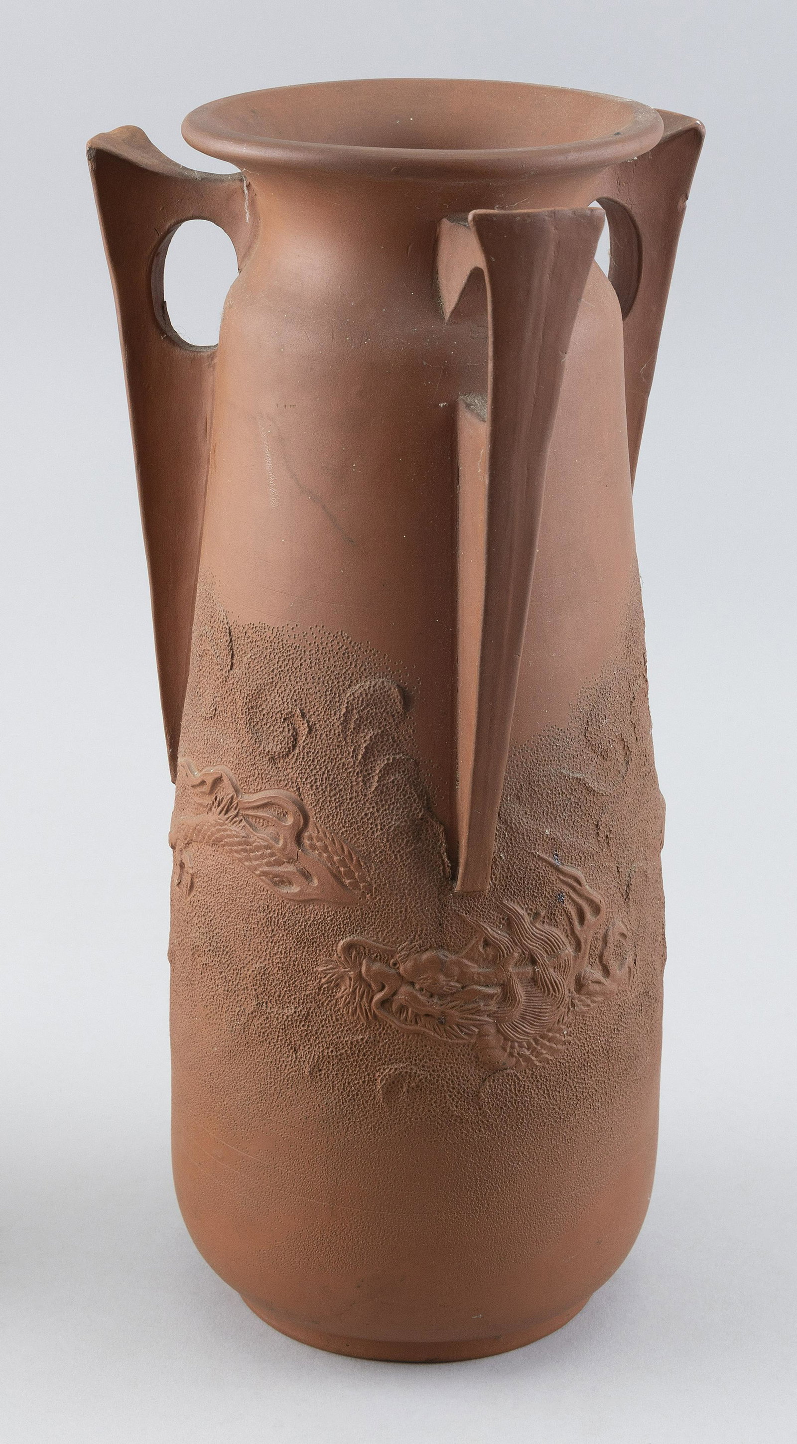 JAPANESE REDWARE POTTERY VASE Early 20th Century Height 12.5".: JAPANESE REDWARE POTTERY VASEEarly 20th CenturyWith three angular handles and a slightly flared mouth. Decoration of a dragon hiding in a stippled landscape.Height 12.5".