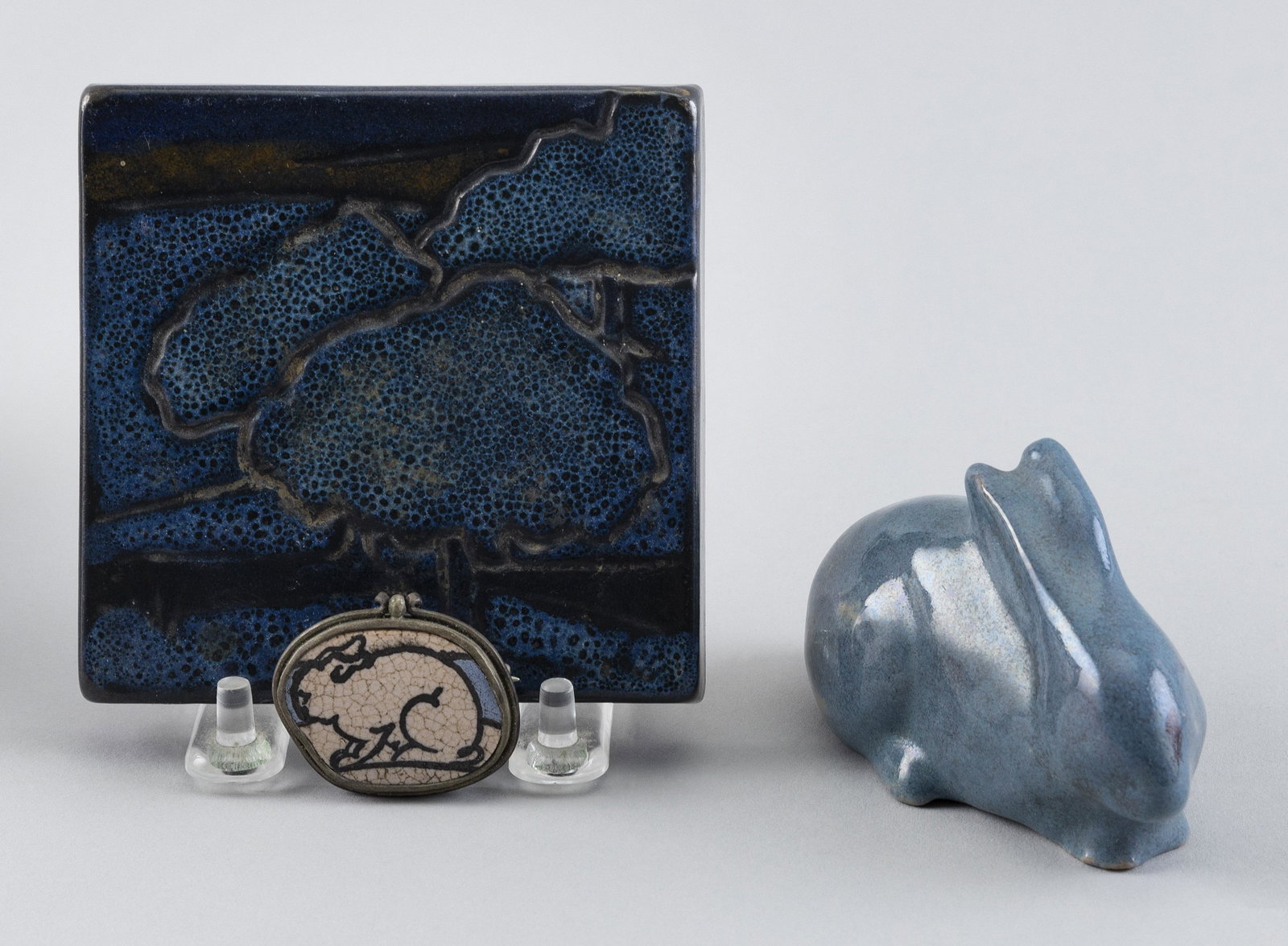 THREE PIECES OF PAUL REVERE AND SATURDAY EVENING GIRLS POTTERY Boston, Early 20th Century Lengths: THREE PIECES OF PAUL REVERE AND SATURDAY EVENING GIRLS POTTERY Boston, Early 20th Century A Saturday Evening Girls rabbit-form paperweight, a Paul Revere trivet with tree design, stamped in ink “