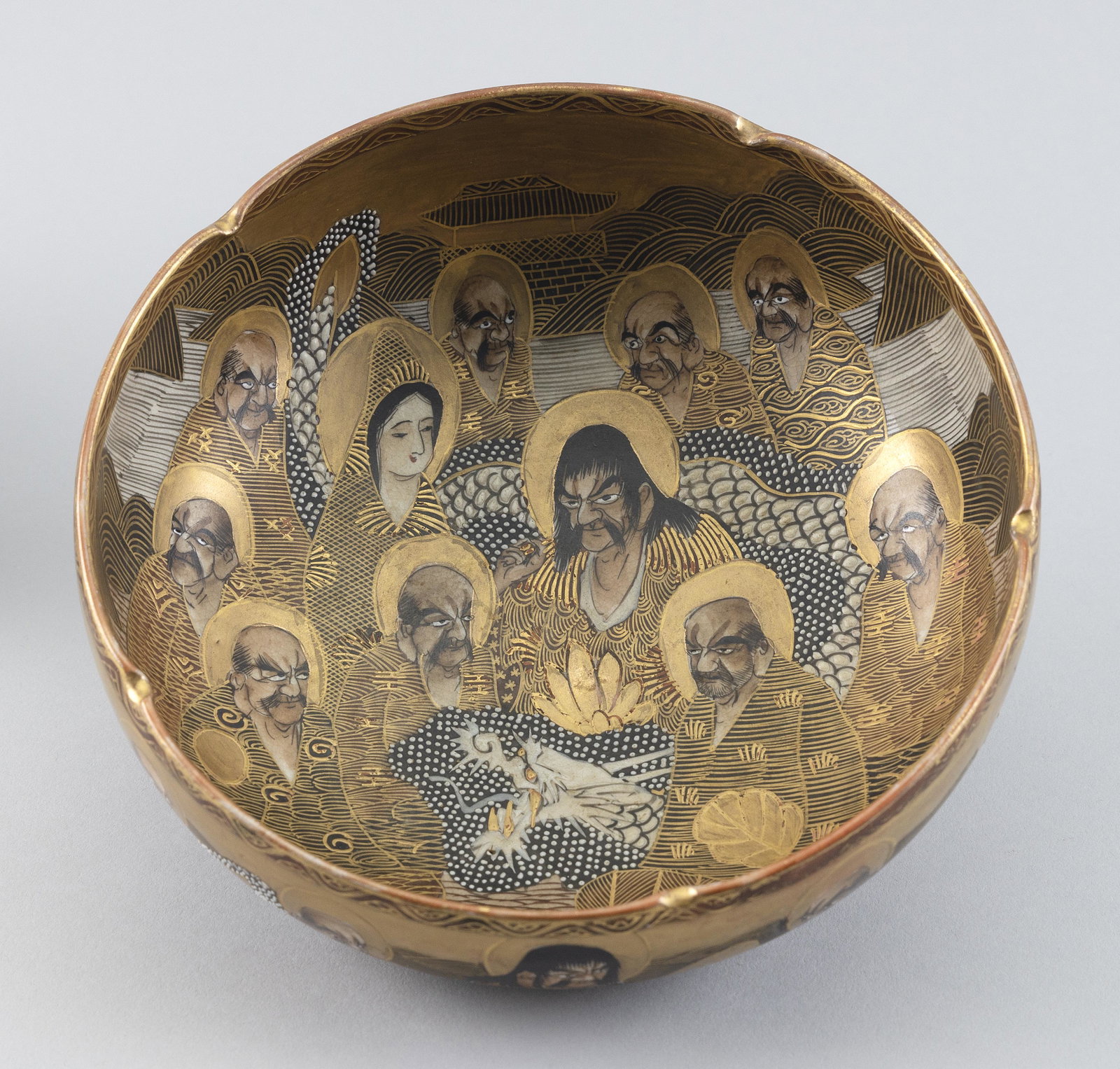 JAPANESE SATSUMA PORCELAIN LOHAN BOWL Late Meiji Period Height 3". Diameter 7".: JAPANESE SATSUMA PORCELAIN LOHAN BOWL Late Meiji Period Pinched rim. Decoration of Immortals and enameled dragon's head on interior. Similar decoration on exterior, with the dragon's body running thro