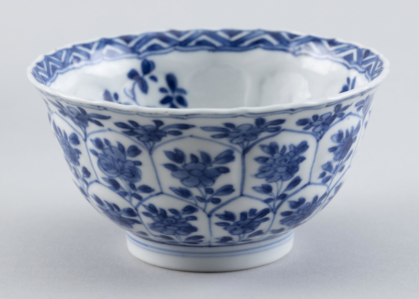 CHINESE BLUE AND WHITE PORCELAIN LOTUS BOWL 19th Century Height 2.25". Diameter 4.5".: CHINESE BLUE AND WHITE PORCELAIN LOTUS BOWL 19th Century Exterior with molded petal design, each petal containing a flower. Interior with similar sprigs and a foliate design at center. Blue censer mar