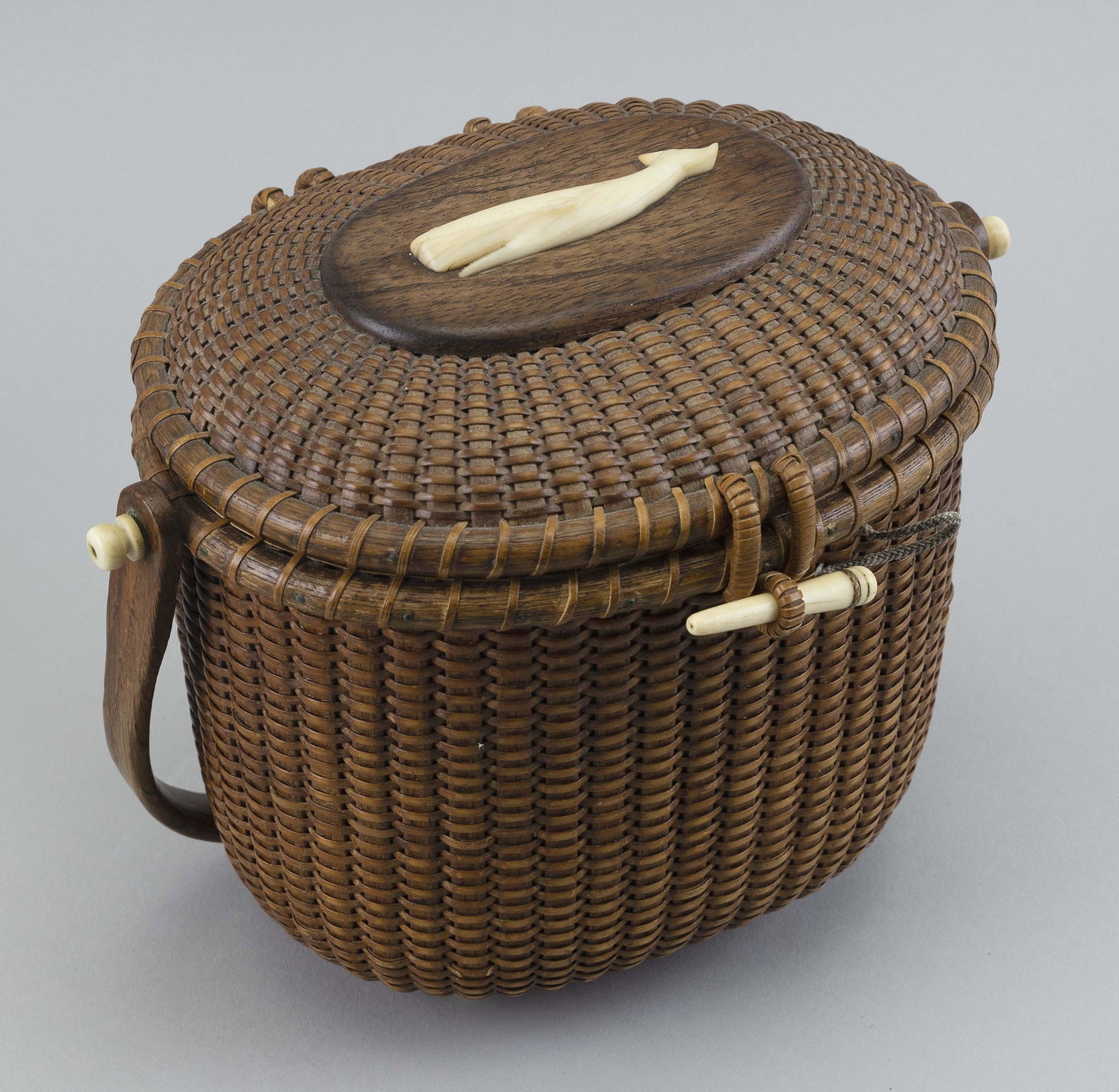 STANLEY ROOP NANTUCKET BASKET PURSE Nantucket, Massachusetts, Dated 1968 Height 7.5”. Length: STANLEY ROOP NANTUCKET BASKET PURSE Nantucket, Massachusetts, Dated 1968 Oval, with swing handle. Carved sperm whale plaque mounted to the top of the hinged lid. Owner's plaque mounted to inside of li