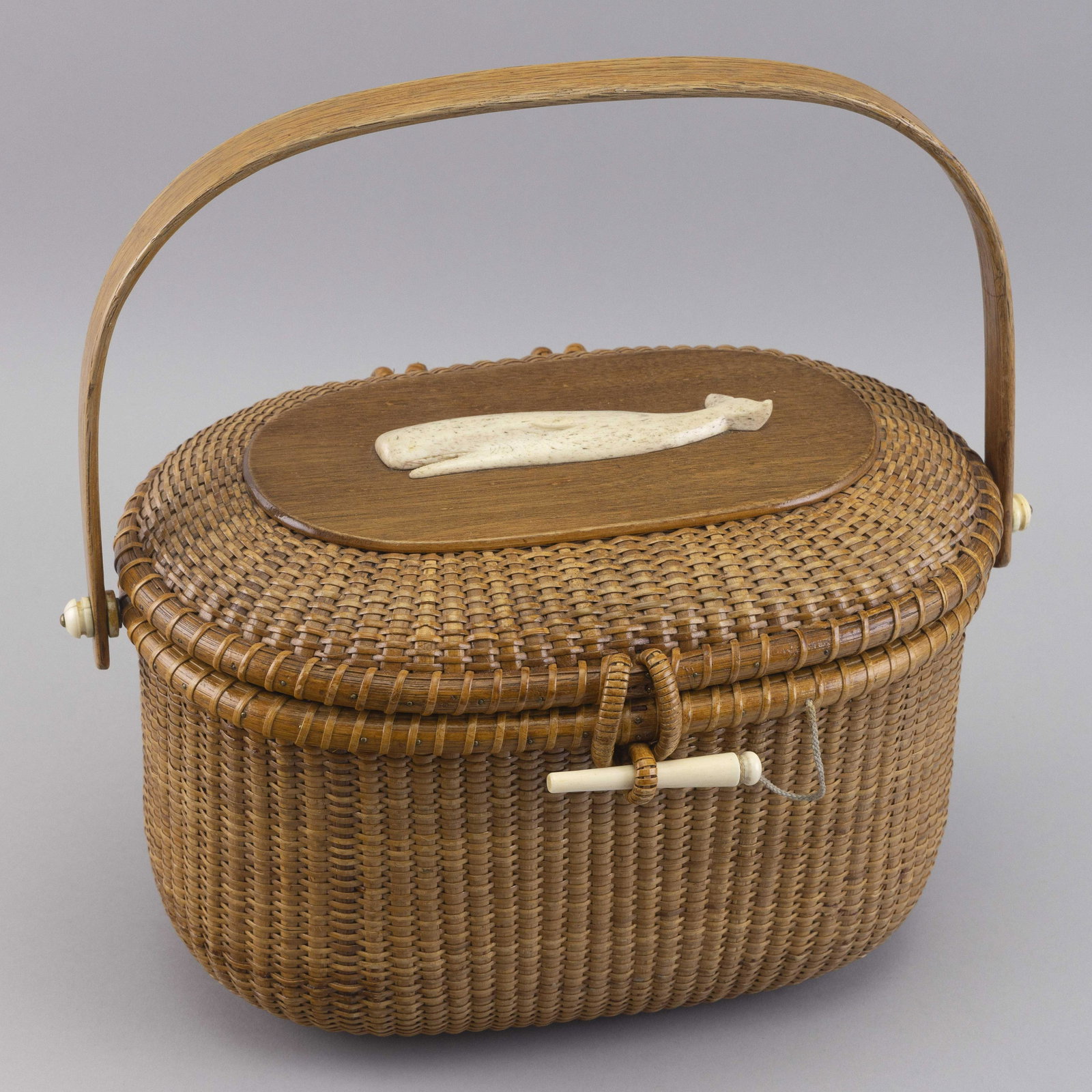 PAUL F. WHITTEN (1909-1997) NANTUCKET BASKET PURSE Dated 1973 Height 8î.: PAUL F. WHITTEN (1909-1997) NANTUCKET BASKET PURSE Dated 1973 Carved sperm whale mounted to top of hinged lid. Signed on interior base. Height 8”. Width 12.25”. Depth approx. 8.5”.