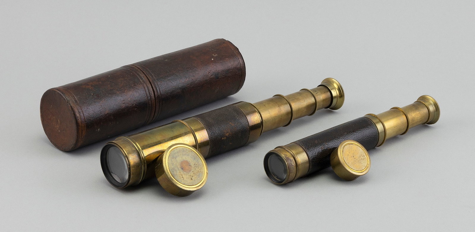 TWO BRASS THREE-DRAW TELESCOPES 19th Century Lengths closed 5î and 6î.: TWO BRASS THREE-DRAW TELESCOPES 19th Century Both with leather-wrapped barrels. One with a leather-wrapped case. Unmarked. Lengths closed 5î and 6î.