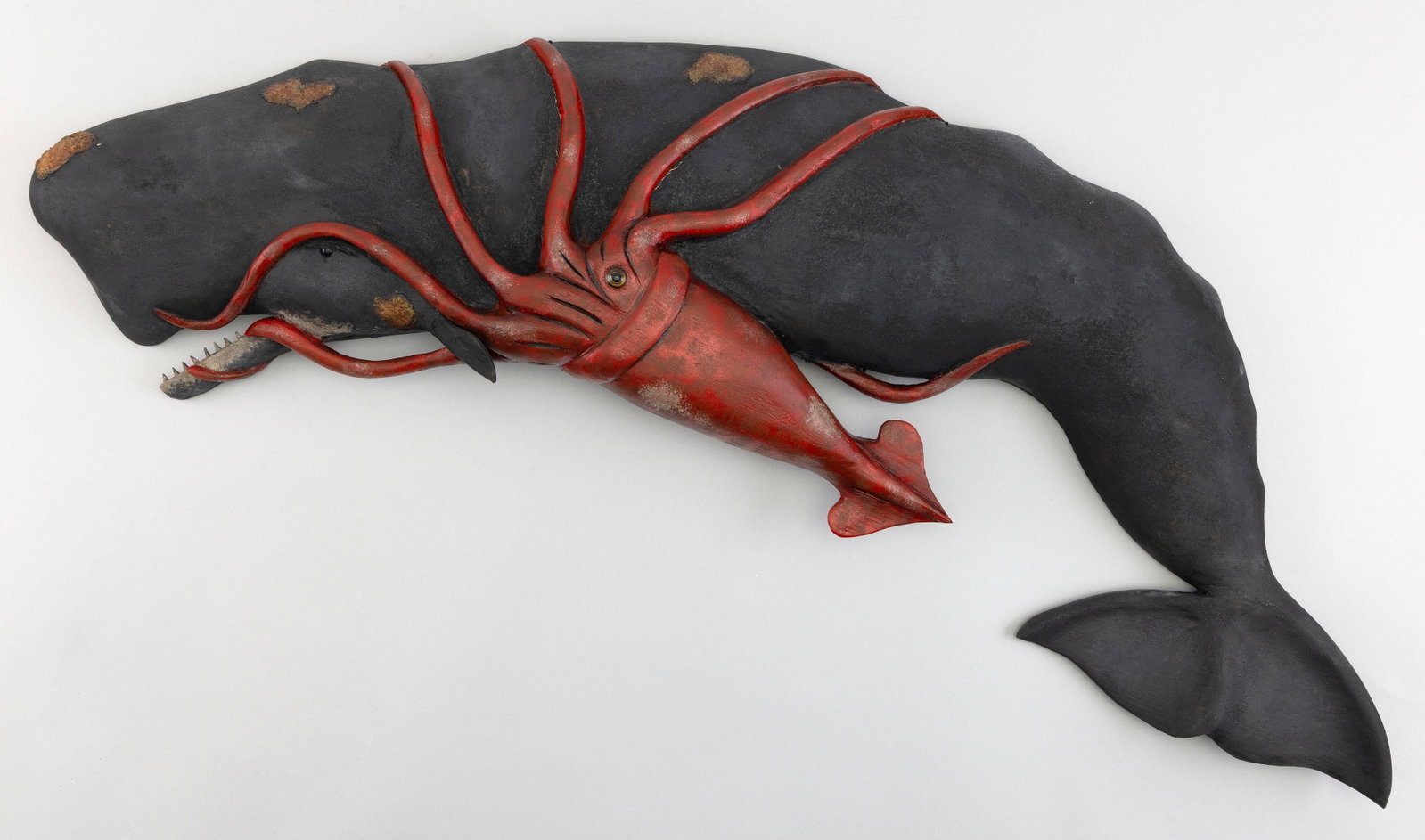 ROGER MITCHELL CARVED AND PAINTED SPERM WHALE PLAQUE Massachusetts, Contemporary Length 32".: ROGER MITCHELL CARVED AND PAINTED SPERM WHALE PLAQUE Massachusetts, Contemporary Being attacked by a giant squid. Signed on back "R. Mitchell". Length 32".