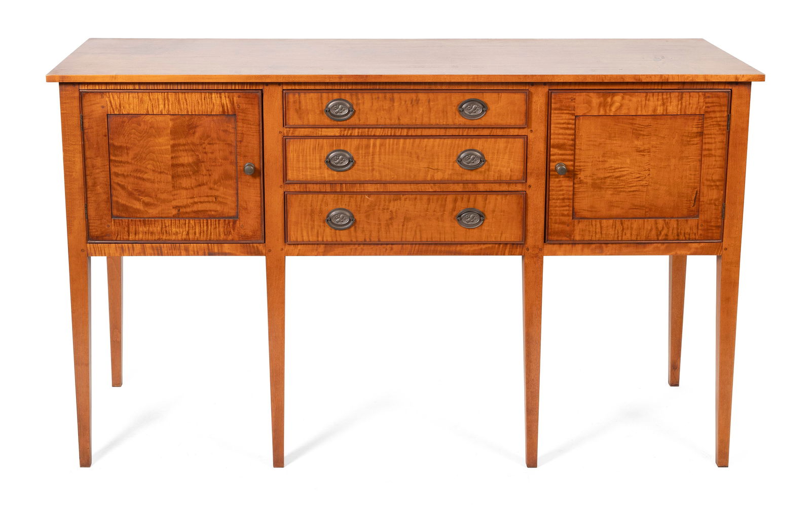 ELDRED WHEELER SIDEBOARD Massachusetts, 20th Century Height 39". Width 64". Depth 21.5".: ELDRED WHEELER SIDEBOARDMassachusetts, 20th CenturyIn tiger maple. Central stack of three drawers flanked by paneled cupboard doors. Square tapered legs. Original Eldred Wheeler label inside a drawer.