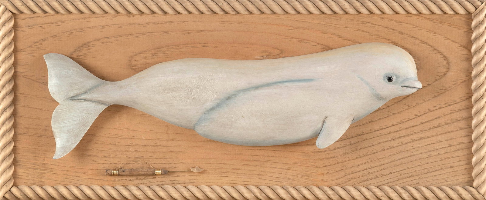 ROGER MITCHELL CARVED WOODEN BELUGA WHALE PLAQUE Massachusetts, Contemporary Length 23".: ROGER MITCHELL CARVED WOODEN BELUGA WHALE PLAQUE Massachusetts, Contemporary Wooden backboard with a rope-carved border. Miniature harpoon affixed to lower left of backboard. Signed on back "R C Mitch