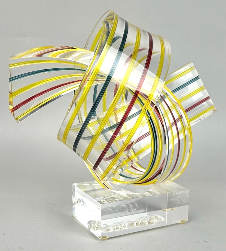 R. GARRETT (America, 20th Century), "Sunglasses", a swirl of yellow, red, clear and blue ribbons.,: R. GARRETTAmerica, 20th Century"Sunglasses", a swirl of yellow, red, clear and blue ribbons. Signed, titled and dated 2000 on base.Lucite, 12" x 7.5".