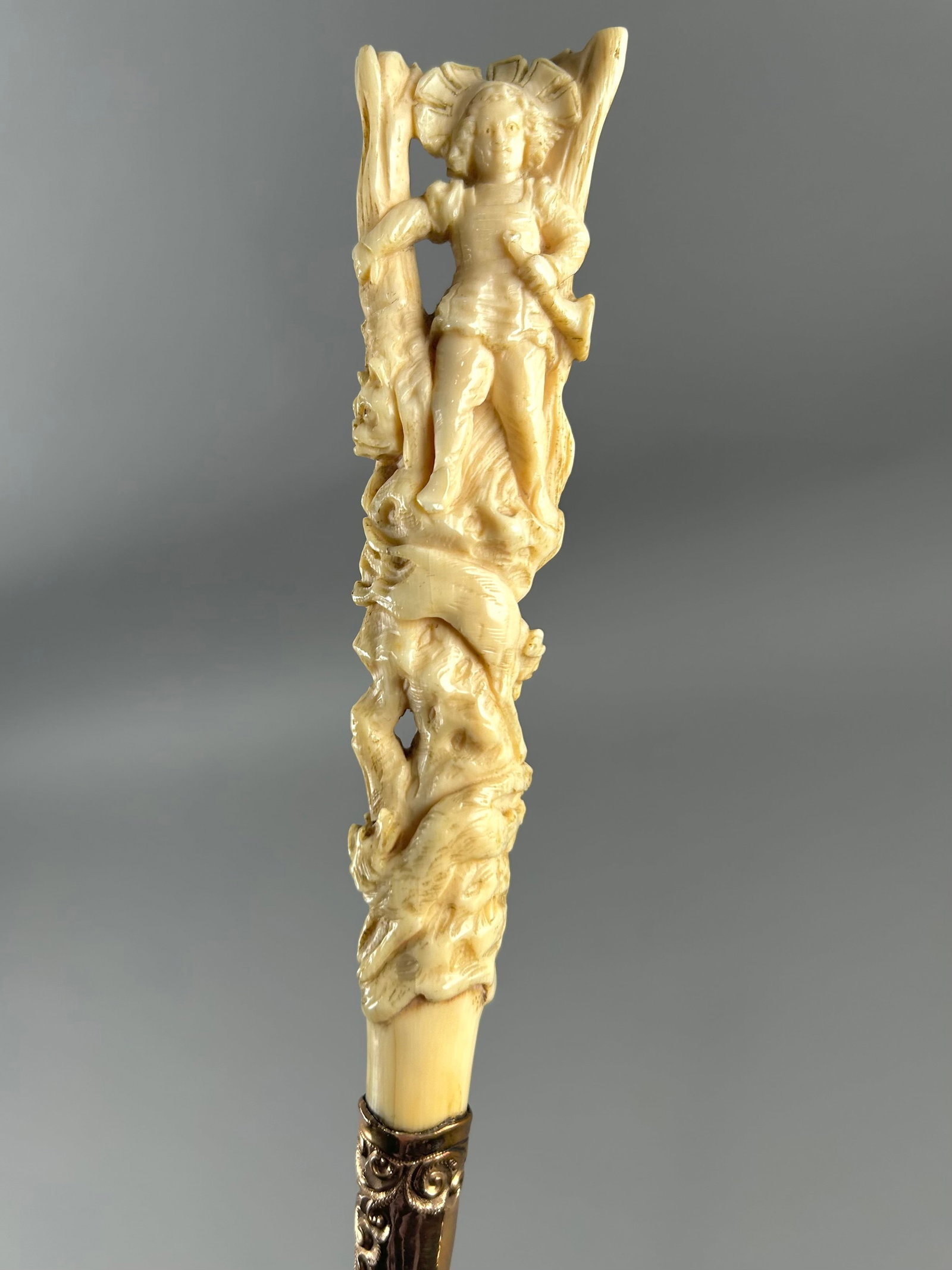 HUNTING SCENE CANE 19th/Early 20th Century Length 37.25".: HUNTING SCENE CANE 19th/Early 20th Century Ivory handle elaborately carved as a huntsman and his hounds amidst woodlands, with the huntsman holding a horn and an animal of prey peering out from behind