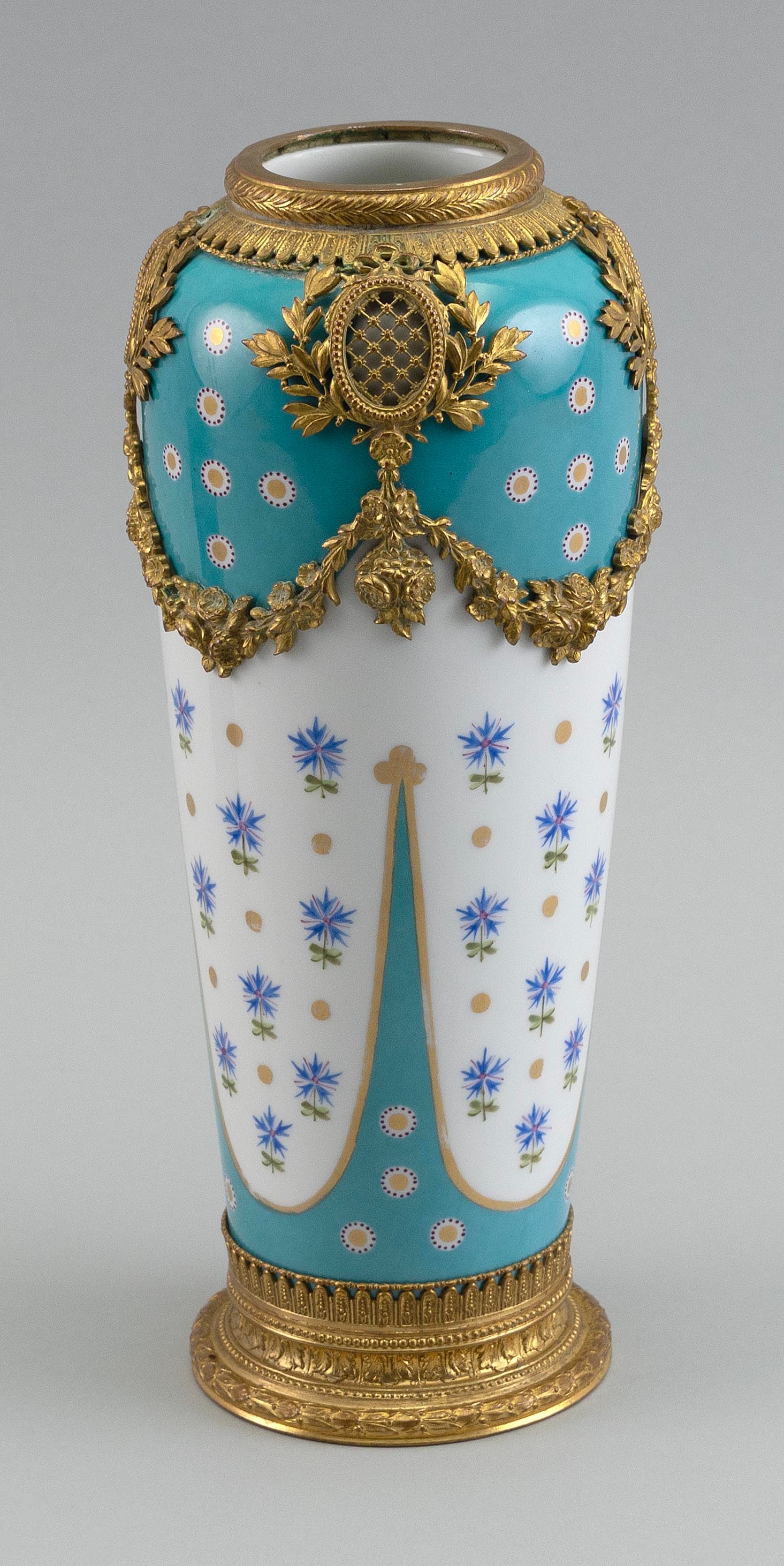 SÈVRES ORMOLU-MOUNTED CELESTE BLUE AND WHITE PORCELAIN VASE Late 19th Century Height 10".: SÈVRES ORMOLU-MOUNTED CELESTE BLUE AND WHITE PORCELAIN VASE Late 19th Century Celeste blue body with gilt and white dots and white swags containing blue cornflowers and gilt dots. Ormolu swag and
