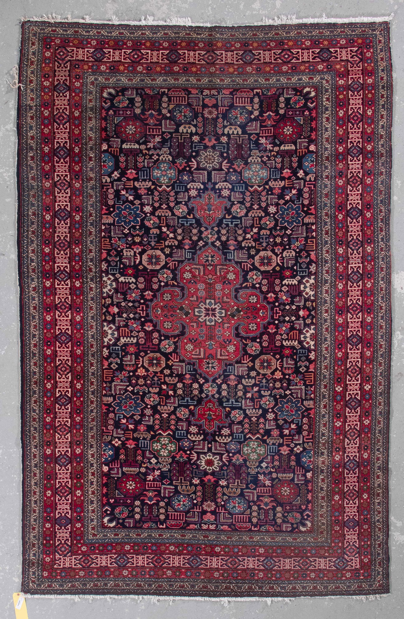 PERSIAN RUG: 9'4" X 6'0" Late 20th Century: PERSIAN RUG: 9'4" X 6'0" Late 20th Century Navy blue field with a red cruciform pedant medallion at center. Dense and neat array of red, blue, green, brassy gold and ivory stylized blossoms and other 