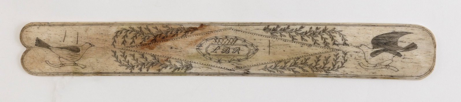 SCRIMSHAW WHALEBONE BUSK 19th Century Length 13".: SCRIMSHAW WHALEBONE BUSK 19th Century Songbirds flank a large diamond containing an "LBR" medallion. Diamond with foliate surround. Reverse with "DR" within a semicircle. Length 13". Provenance: Rafae