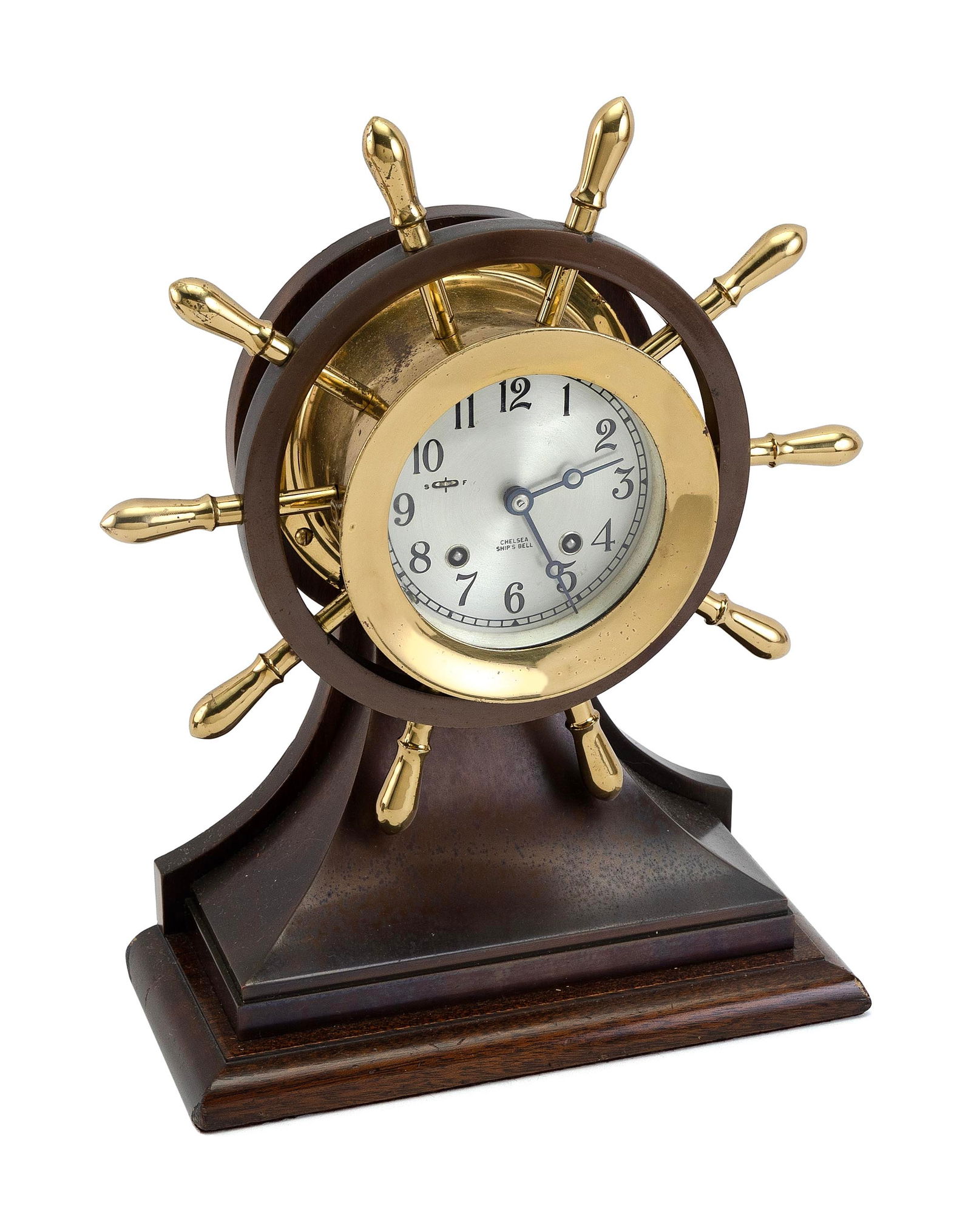 CHELSEA CLOCK CO. "MARINER" SHIP'S BELL CLOCK Boston, Circa 1960s Dial diameter 4.5". Height 14".: CHELSEA CLOCK CO. "MARINER" SHIP'S BELL CLOCKBoston, Circa 1960sBrass and bronze-finish ship's wheel case on wooden base. Hinged bezel. Silvered Arabic numeral dial marked "Chelsea Ship's Bell". Eight