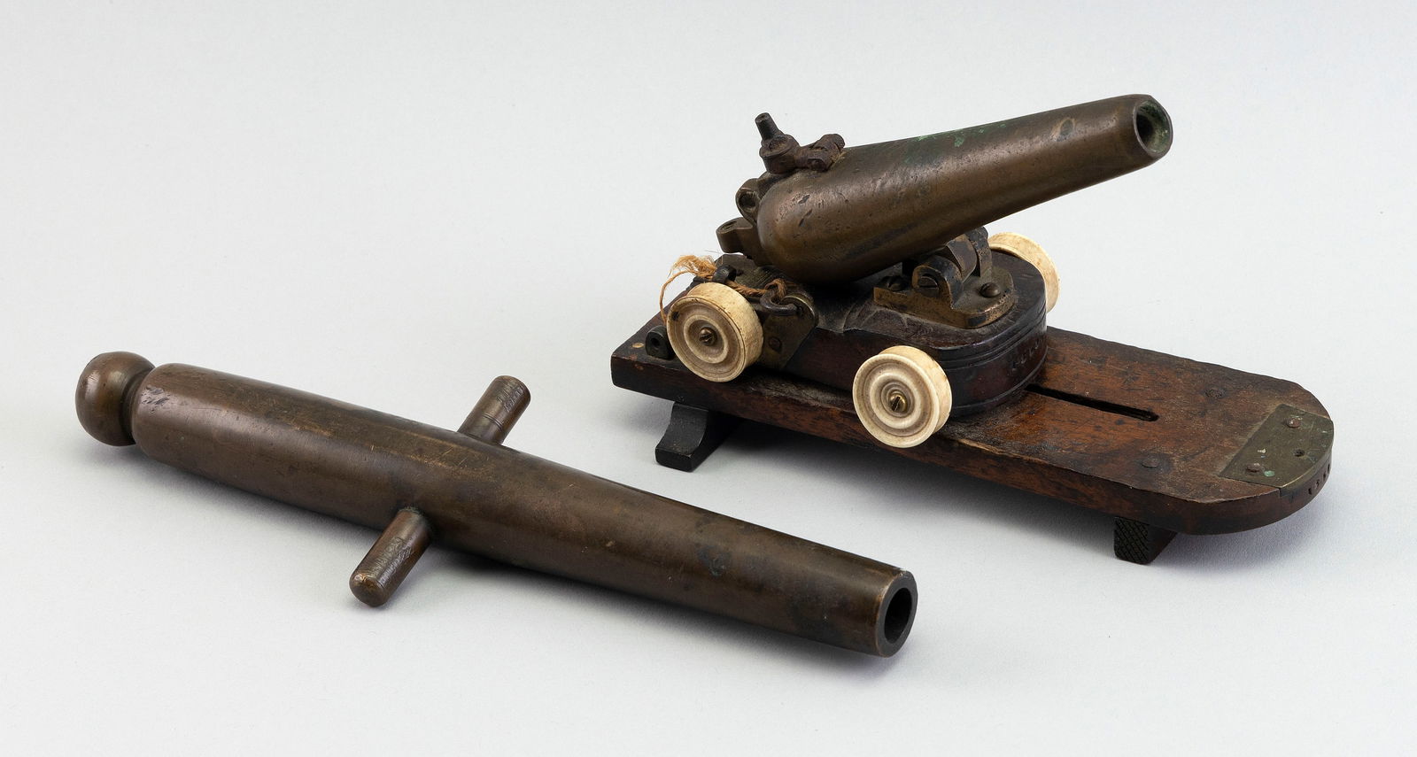 TWO BRONZE CANNONS Second Half of the 19th Century Barrel lengths 7.5" and 9.5".: TWO BRONZE CANNONSSecond Half of the 19th CenturyA cannonade marked on wood frame "1850" and a cannon barrel marked "USN".Barrel lengths 7.5" and 9.5".