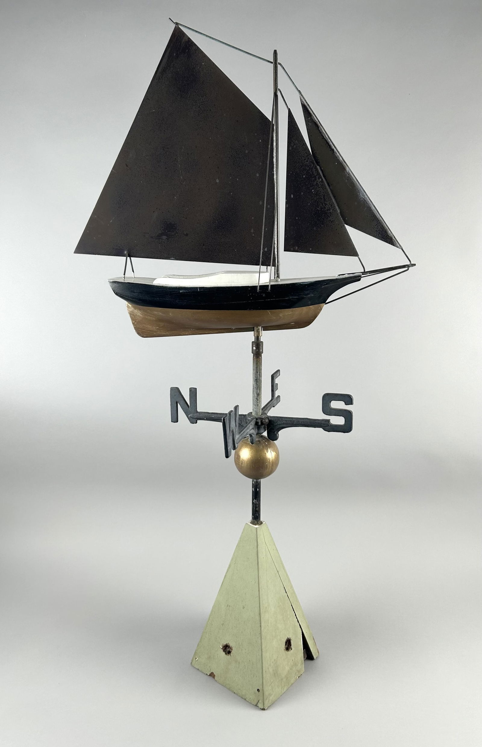 SAILBOAT WEATHER VANE ON STAND Early 20th Century Height 39". Length 19".: SAILBOAT WEATHER VANE ON STANDEarly 20th CenturySailboat with wooden hull and metal sails. Mounted with directionals on a wooden stand.Height 39". Length 19".
