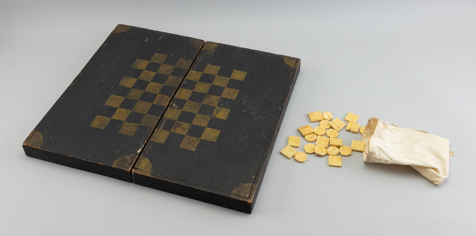 SEA CAPTAIN'S FOLDING WOODEN GAME BOARD 19th Century Folded height 3". Top 9" x 16.5".: SEA CAPTAIN'S FOLDING WOODEN GAME BOARD 19th Century Found in New Bedford, Massachusetts. Painted black and yellow. Includes 24 playing pieces (12 shaped as octagons, 12 shaped as squares). Folded hei