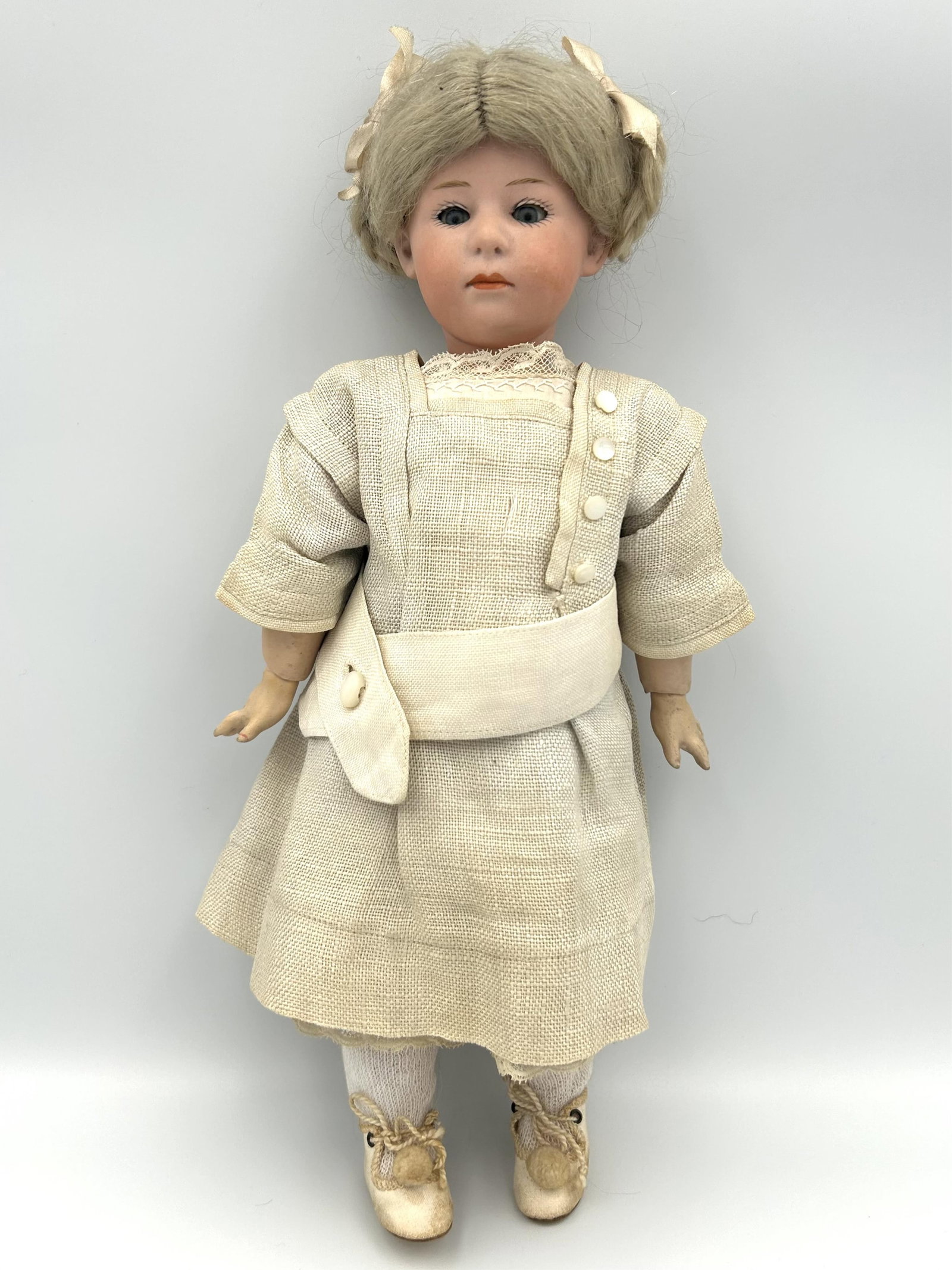 GEBRUDER HEUBACH 6969 POUTY FACE BISQUE-HEAD DOLL Germany, Circa 1910 Height 11".: GEBRUDER HEUBACH 6969 POUTY FACE BISQUE-HEAD DOLL Germany, Circa 1910 With blonde wig, blue sleep eyes and composition ball-jointed body. Wearing an off-white dress. Height 11".