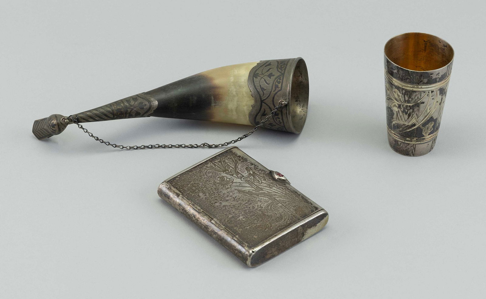 THREE CONTINENTAL SILVER BAR ACCESSORIES 19th/20th Century: THREE CONTINENTAL SILVER BAR ACCESSORIES19th/20th Century1) Jigger with exterior alternating paneled faux bois and floral decoration. Gilt-washed interior. "AC" hallmark on base. Height 3".2) Cigarett