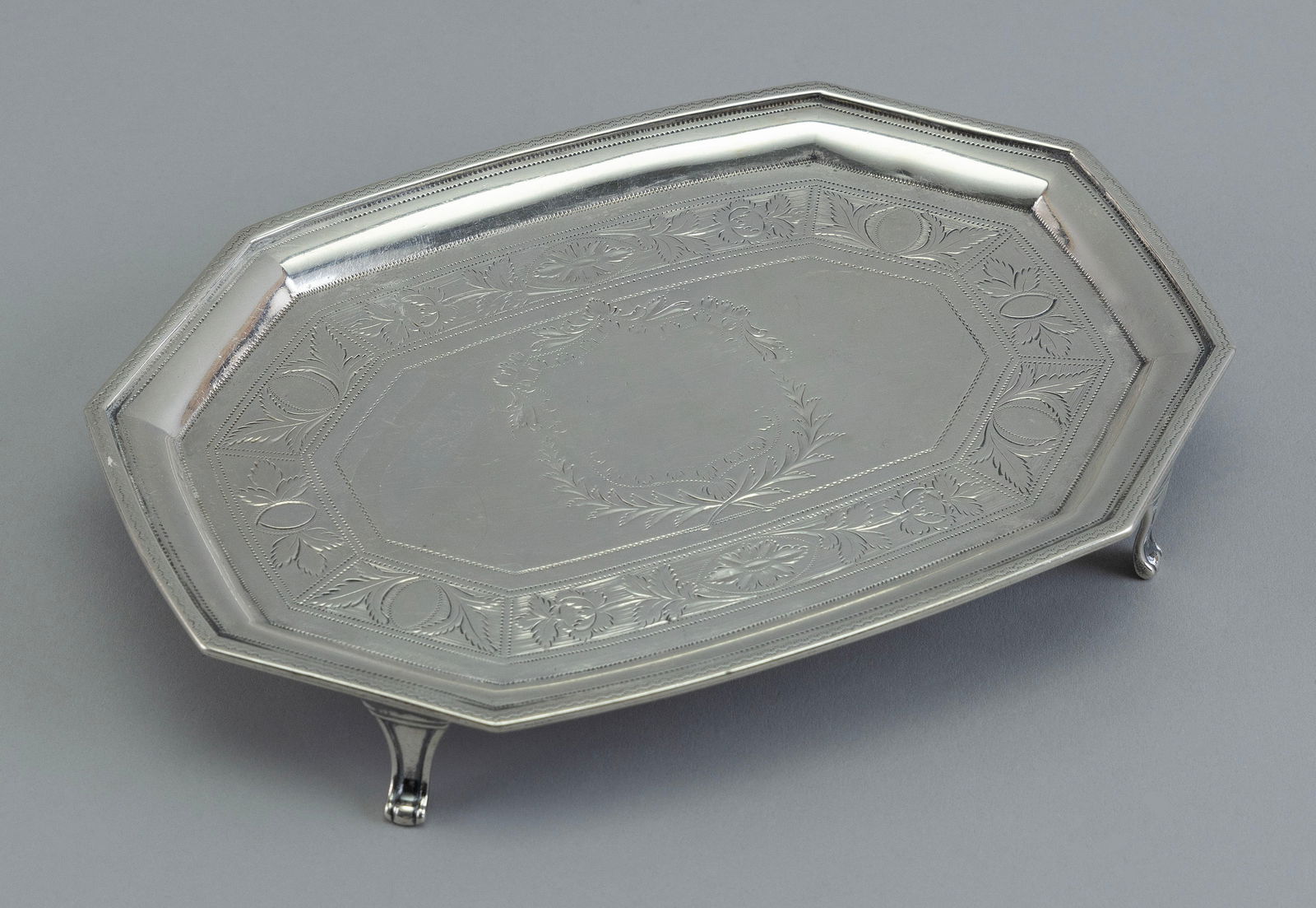 ROBERT & DAVID HENNELL GEORGIAN SILVER SALVER London, Late 18th Century Approx. 4.5 troy oz.: ROBERT & DAVID HENNELL GEORGIAN SILVER SALVERLondon, Late 18th CenturyOctagonal and raised on four feet. Engraved heraldic shield and floral band. Date letter for 1795. 7" x 4.75".Approx. 4.5 troy oz.