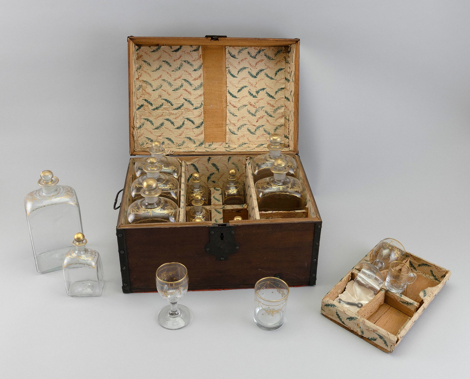 OAK LIQUOR CHEST 19th Century Height 10". Width 15.5". Depth 10.5".: OAK LIQUOR CHEST 19th Century Iron mounts. Includes 12 gilt-decorated blown glass bottles and four small glasses. Height 10". Width 15.5". Depth 10.5".