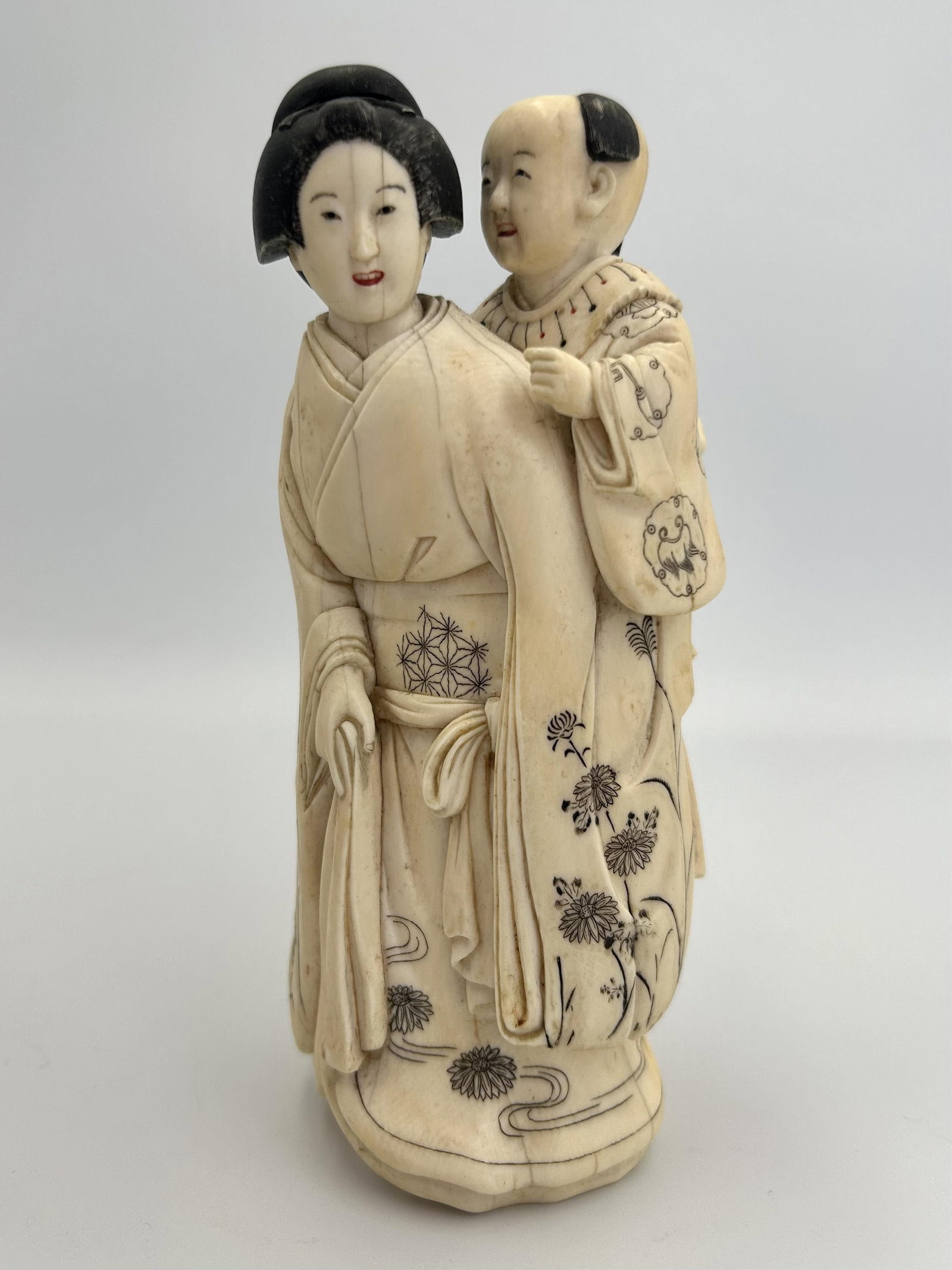 JAPANESE CARVED IVORY FIGURE GROUP Late 19th Century Height 6".: JAPANESE CARVED IVORY FIGURE GROUP Late 19th Century Woman in floral robes with a small child on her back. Traces of polychroming. Signed on base. Height 6".