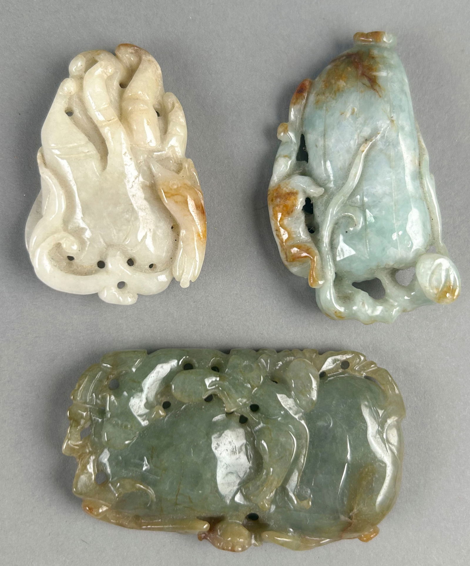 THREE CHINESE CARVED CELADON JADE PENDANTS Lengths from 1.75" to 2.5". (1 of 2)