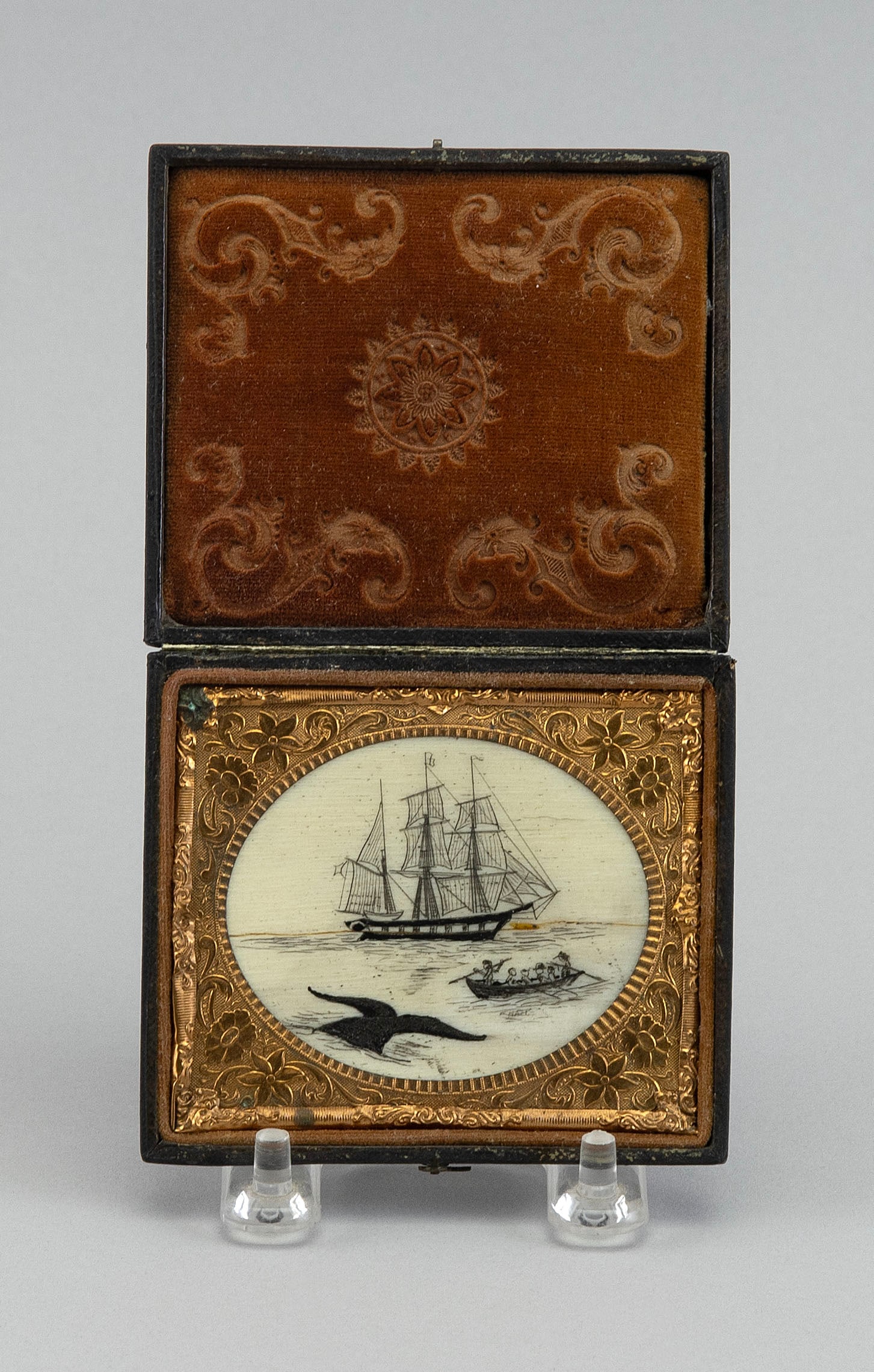 * ENGRAVED WHALEBONE PANEL DEPICTING A WHALING SCENE 20th Century Approx. 2" x 2.5" sight. Case: * ENGRAVED WHALEBONE PANEL DEPICTING A WHALING SCENE 20th Century Housed in a 19th Century folding photo case. Panel depicts a whaleship and a whaleboat approaching a surfaced whale. Signed below whal