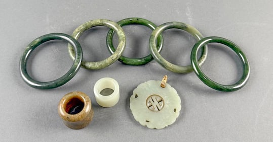 EIGHT JADE JEWELRY ITEMS Bangle diameters 3". Ring heights 1" and 1.25". Pendant diameter 2.25".