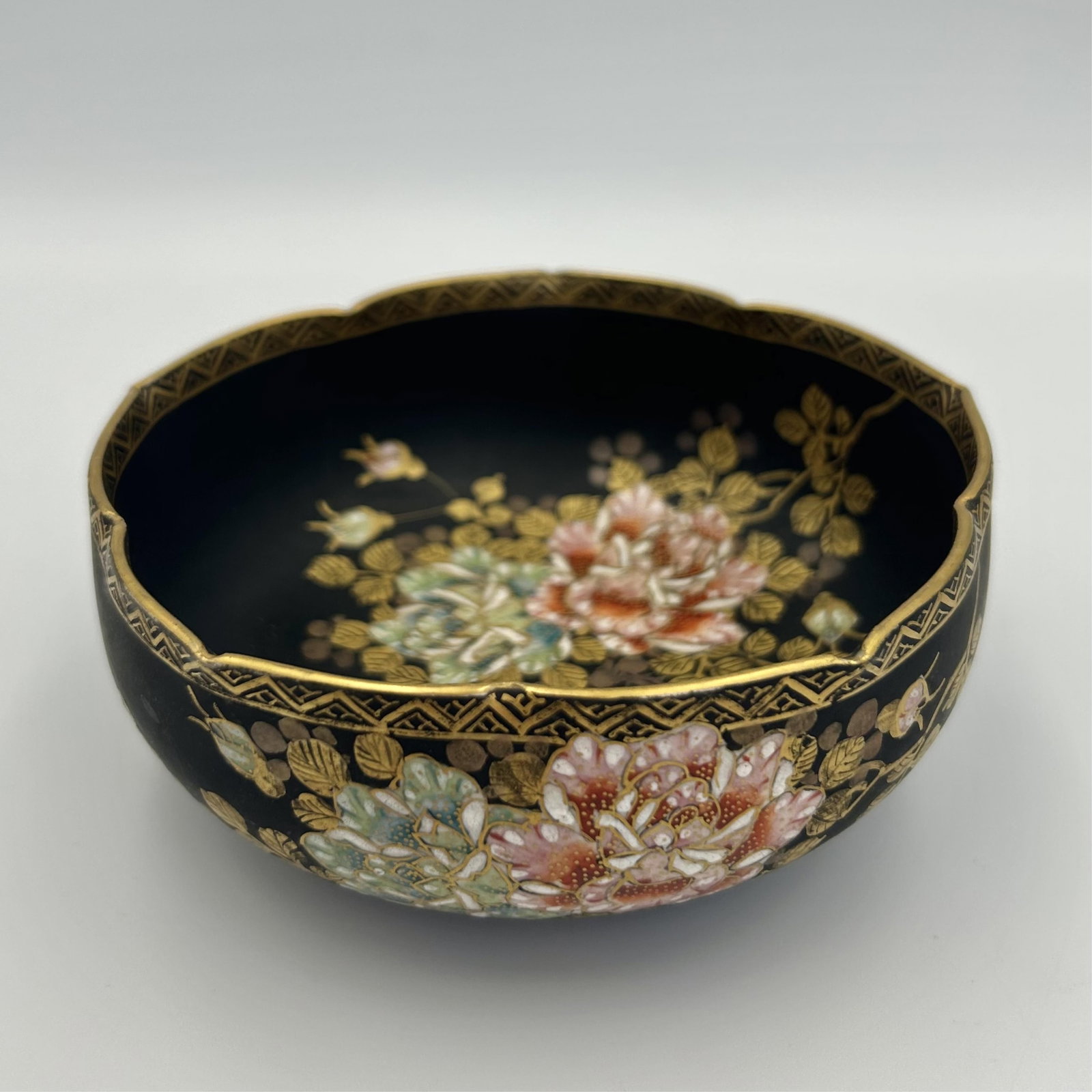 JAPANESE KYO SATSUMA PORCELAIN LOTUS BOWL Meiji Period, Late 19th Century Height 2". Length 5".: JAPANESE KYO SATSUMA PORCELAIN LOTUS BOWL Meiji Period, Late 19th Century Enameled floral decoration with gilt highlights against a matte black ground. Gilt brocade shaped edge. Signed on base. Height