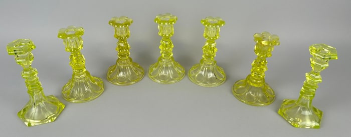 SEVEN CANARY YELLOW PRESSED GLASS CANDLESTICKS 19th Century Heights from 9.5" to 11.25".