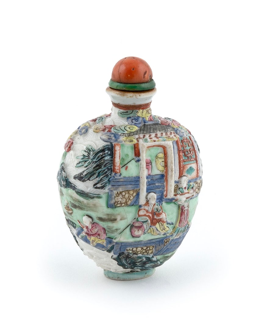FAMILLE ROSE MOLDED PORCELAIN SNUFF BOTTLE Late 19th/Early 20th Century Height 2.75".: FAMILLE ROSE MOLDED PORCELAIN SNUFF BOTTLE Late 19th/Early 20th Century Spade form. Decoration of figures at various pursuits in a courtyard landscape over rolling waves. Coral stopper. Four-character