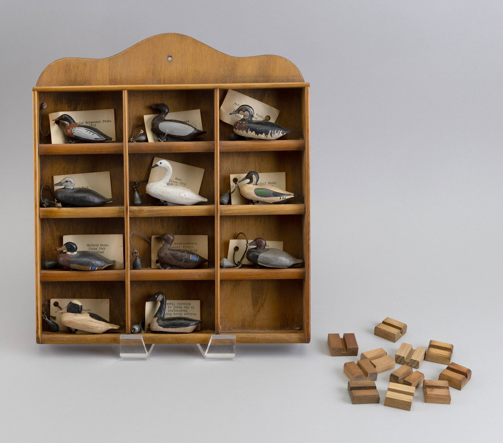 COLLECTION OF ELEVEN MINIATURE DECOYS IN A WOODEN DISPLAY CASE 20th Century Decoy lengths approx.: COLLECTION OF ELEVEN MINIATURE DECOYS IN A WOODEN DISPLAY CASE 20th Century Carved and painted replicas of antique decoys, each with a typed description, lead weight and wood stand. Tags marked on rev