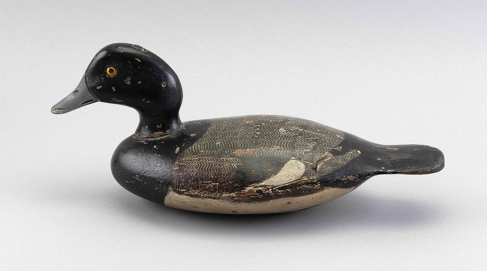 STEVENS DECOY FACTORY BLUEBILL DRAKE DECOY Weedsport, New York, Late 19th Century Length 13.5".: STEVENS DECOY FACTORY BLUEBILL DRAKE DECOY Weedsport, New York, Late 19th Century Glass eyes. Comb painting on back. Extended paddle tail. Length 13.5". Provenance: An Upstate New York Collection.