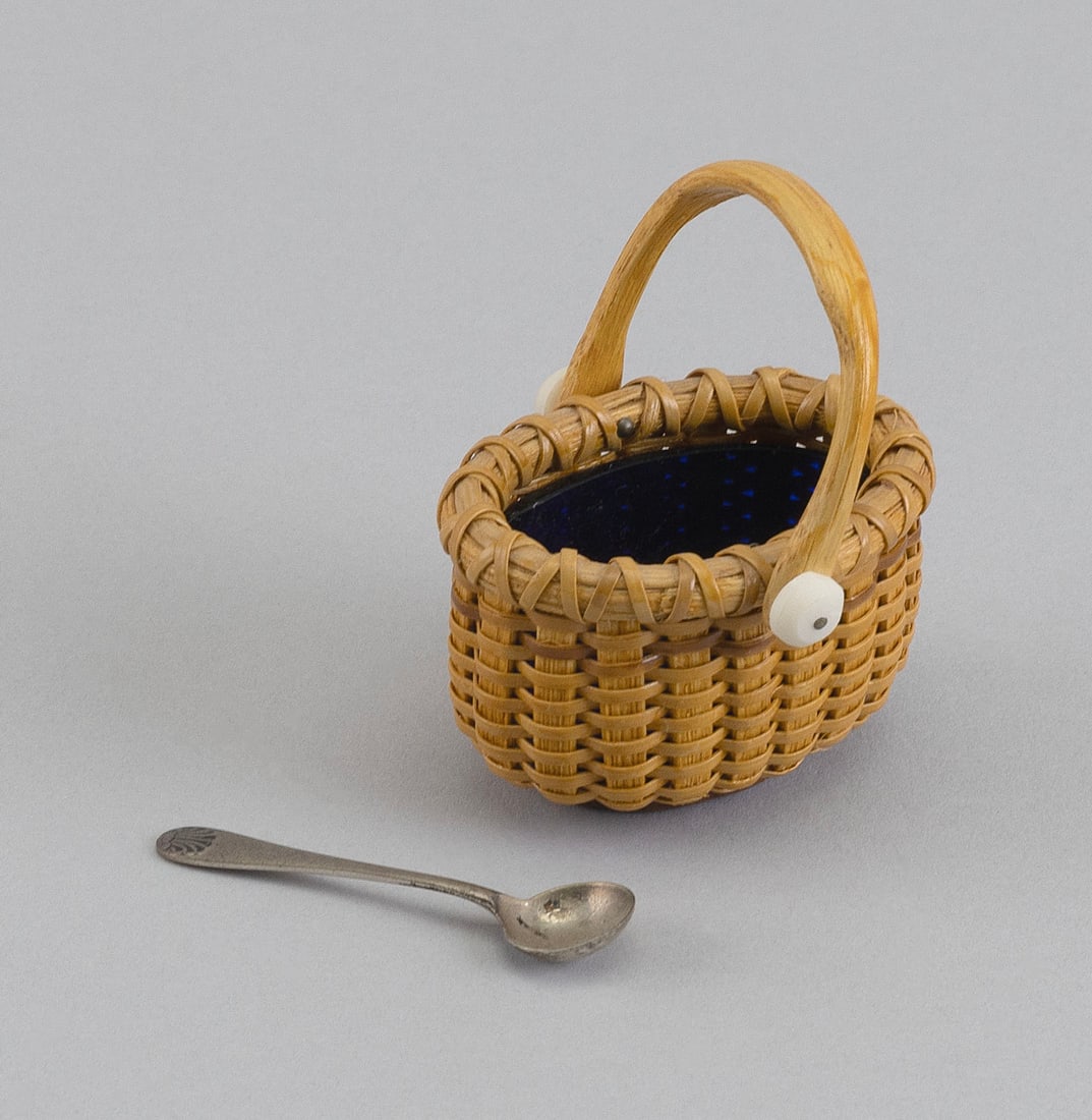 PAUL WILLER MINIATURE NANTUCKET BASKET SALT Nantucket, Late 20th Century Height to rim 1.5". Length: PAUL WILLER MINIATURE NANTUCKET BASKET SALT Nantucket, Late 20th Century Together with a hallmarked silver salt spoon with shell terminal. Oval basket with swing handle and fitted with a cobalt blue g