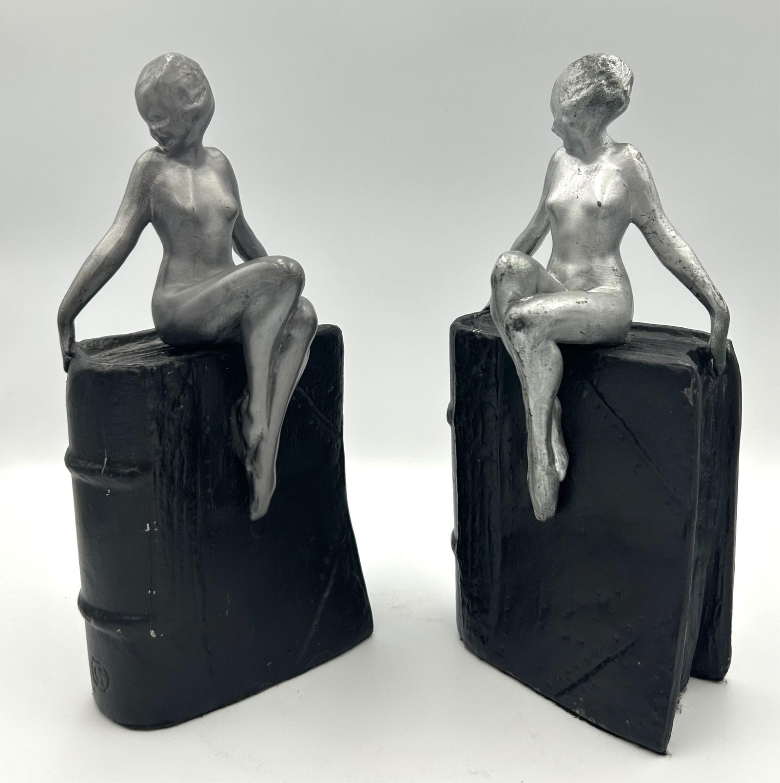 PAIR OF FRANKART, INC. ART DECO CAST METAL FIGURAL BOOKENDS New York, 20th Century Heights 10.5".: PAIR OF FRANKART, INC. ART DECO CAST METAL FIGURAL BOOKENDSNew York, 20th CenturyFormed as a silvered nude atop a brown book. Marked on spine.Heights 10.5". Lengths 4.5".