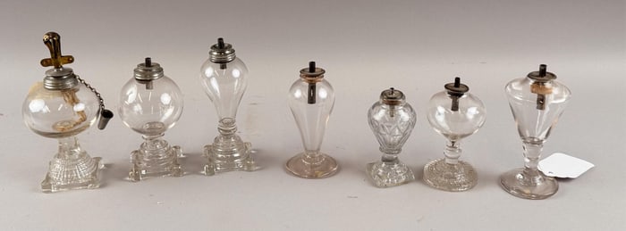SEVEN CLEAR GLASS SPARKING LAMPS First Half of the 19th Century Heights from 3.75" to 4.75".