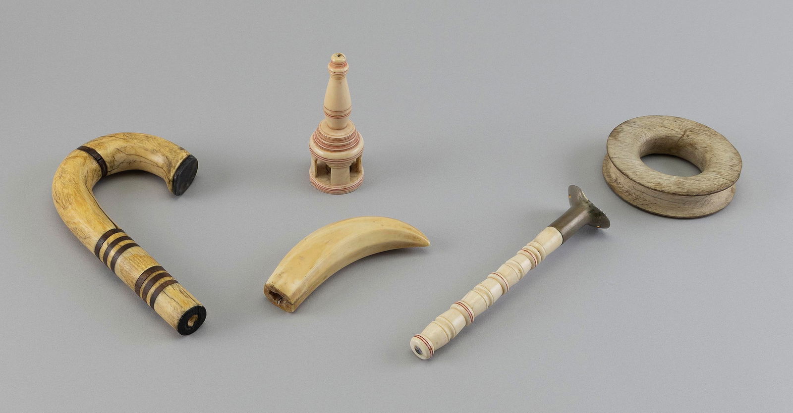 FIVE CARVED BONE AND IVORY UTILITARIAN ITEMS 19th Century Lengths from 4.5" to 7.5".: FIVE CARVED BONE AND IVORY UTILITARIAN ITEMS19th CenturyTwo cane handles, a dipper handle, a rigging thimble and a finial.Lengths from 4.5" to 7.5".